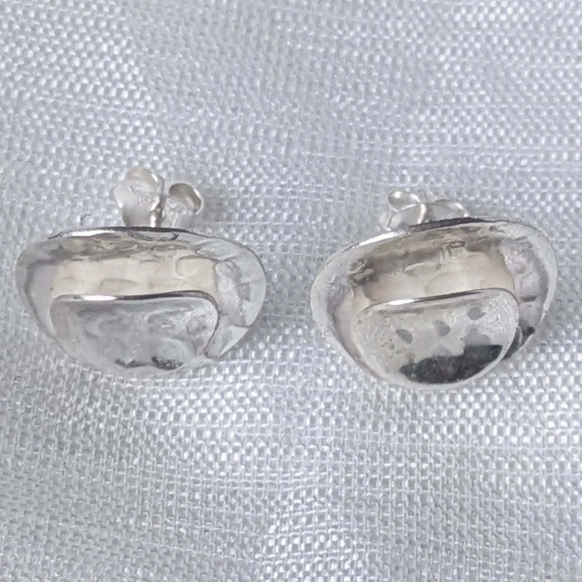 Frontalansicht der markanten, kreisrunden Silberohrstecker, die die strukturierte Oberfläche zeigt.