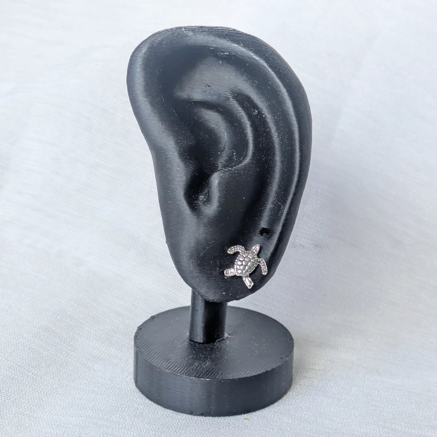 Schildkröten Ohrstecker Silber präsentiert an einem schwarzen Schmuck-Display.