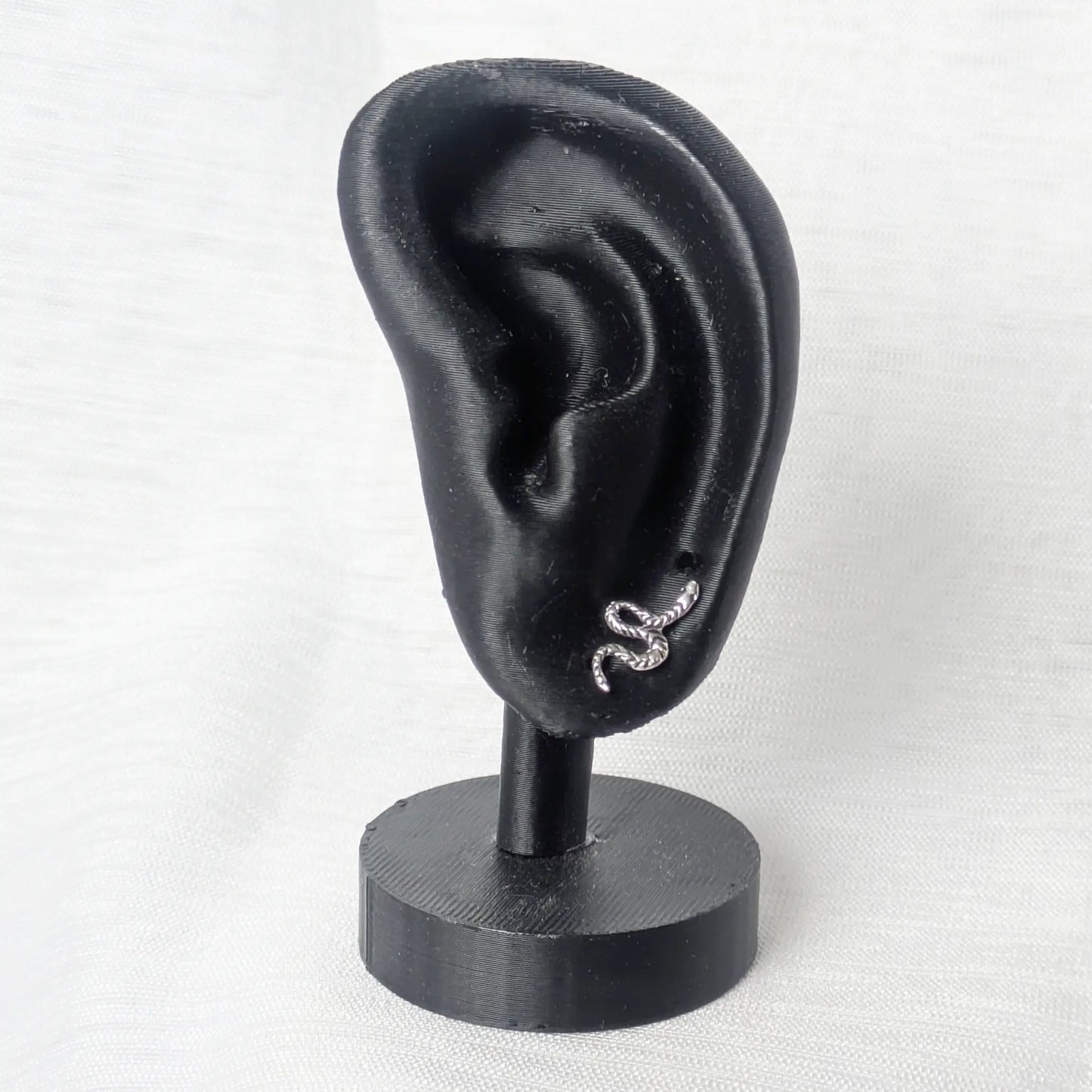 Schlangen Ohrstecker Silber elegant präsentiert an einem schwarzen Ohr-Display.
