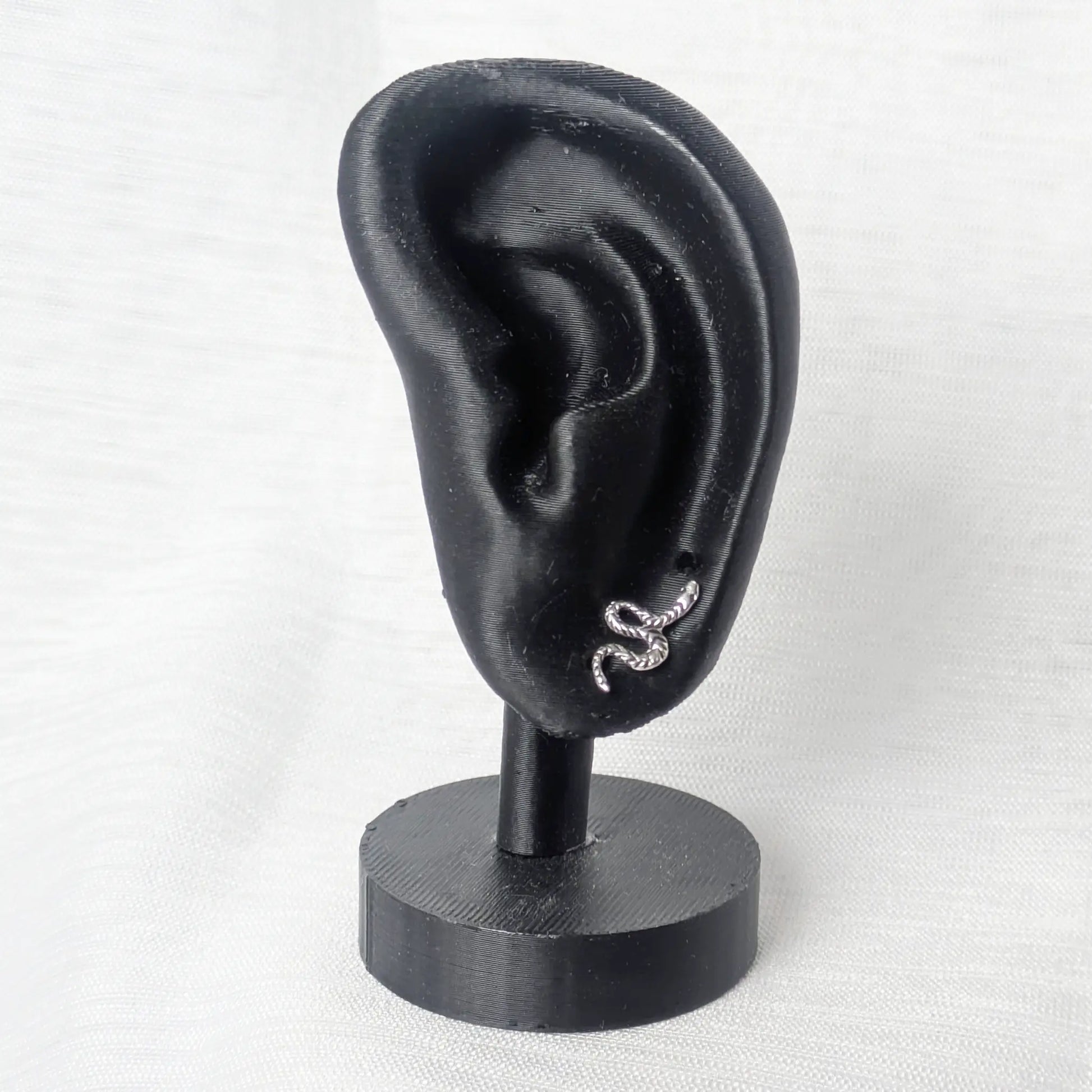 Schlangen Ohrstecker Silber elegant präsentiert an einem schwarzen Ohr-Display.