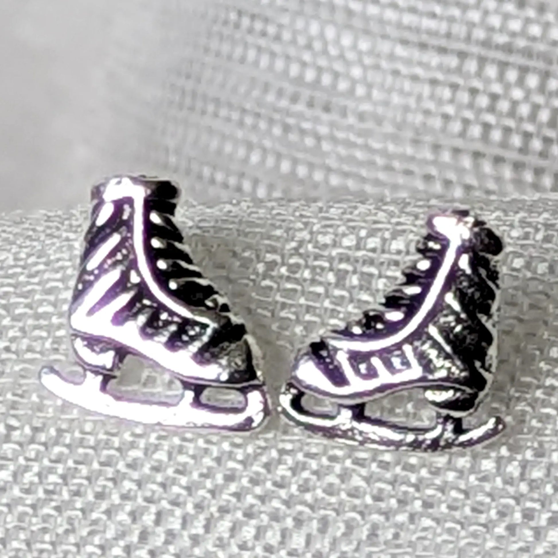 Detailreiche Nahaufnahme von zwei Schlittschuh Ohrsteckern aus 925 Sterling Silber mit geschwärzten Details an Schnürung und Kufen.