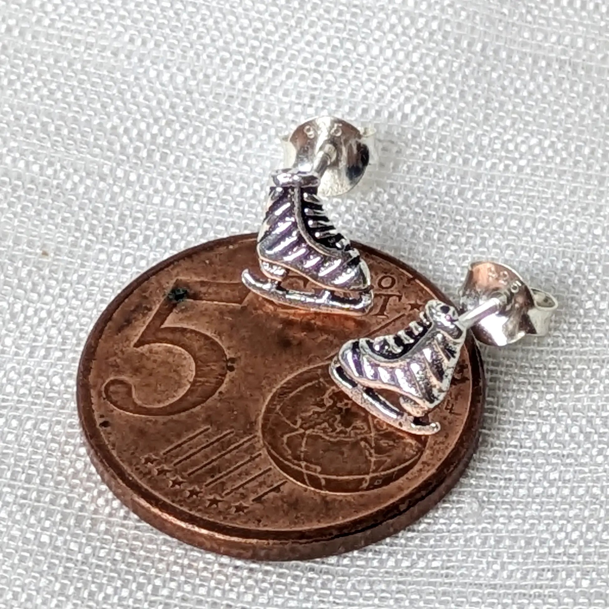 Größenvergleich der zarten, silbernen Eiskunstlauf-Ohrstecker platziert auf einer 5-Cent-Münze.