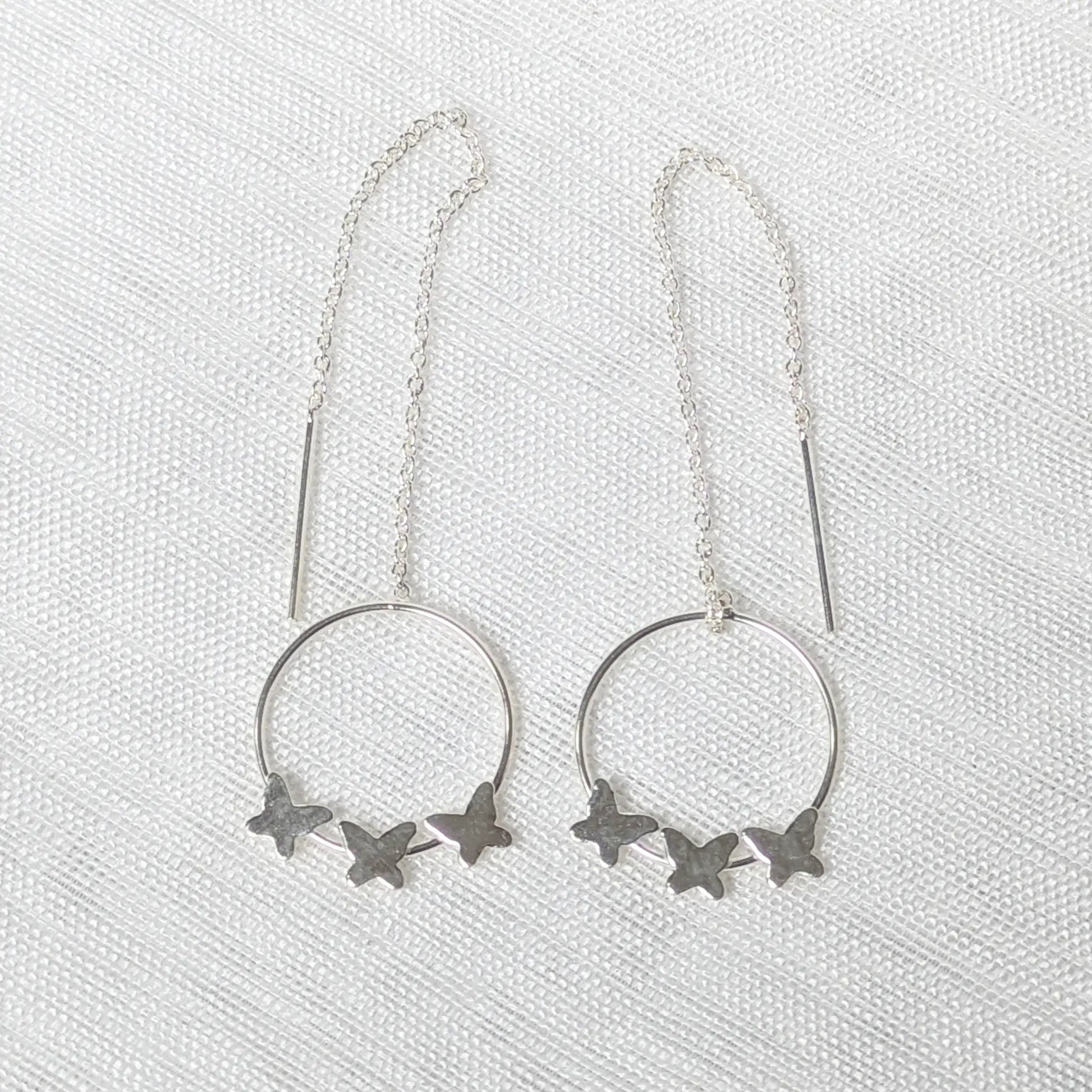 Nahaufnahme von filigranen 925 Silber-Durchziehohrringen mit drei kleinen Schmetterlingen auf einem runden Element.