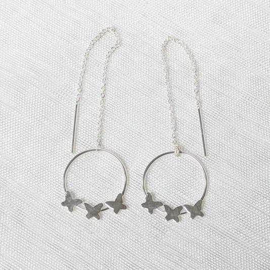 Nahaufnahme von filigranen 925 Silber-Durchziehohrringen mit drei kleinen Schmetterlingen auf einem runden Element.