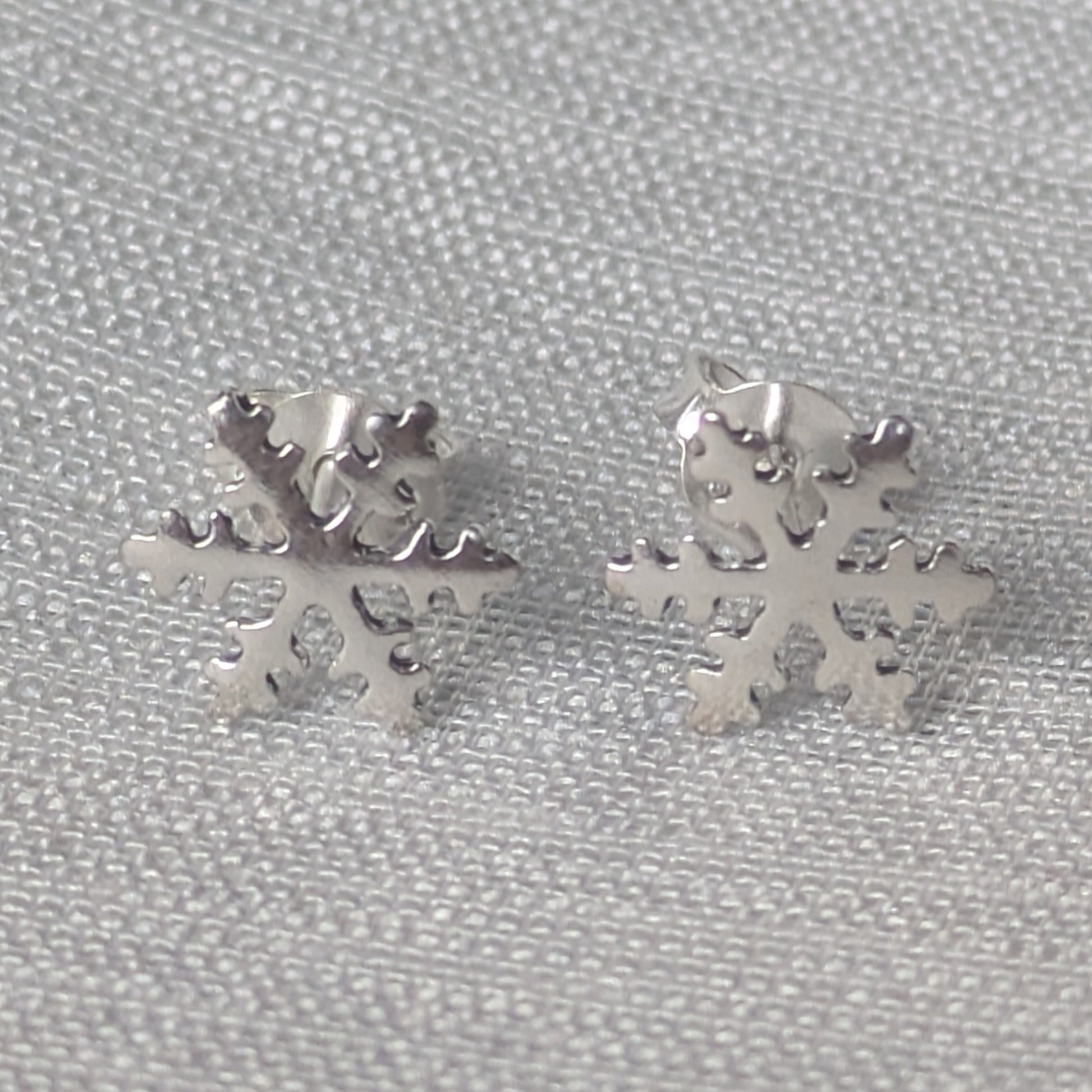 Frontalansicht der glänzenden Schneeflocke Ohrstecker aus 925 Sterling Silber auf hellem Hintergrund.
