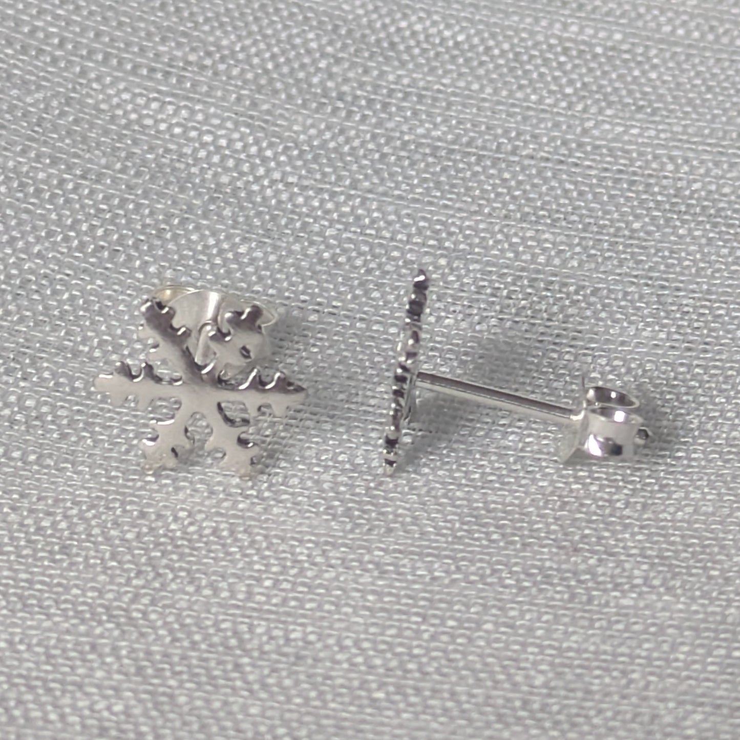 Seitliche Ansicht eines filigranen Silber-Ohrsteckers in Schneeflockenform, zeigt den Stecker-Verschluss.