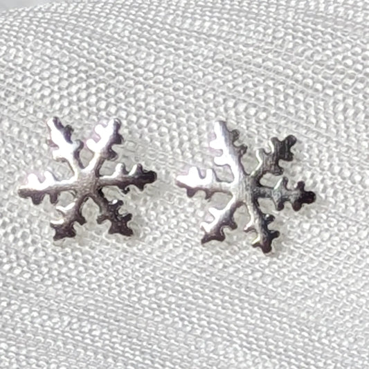 Detailreiche Nahaufnahme von zwei hochglanzpolierten Schneeflocken Ohrsteckern aus echtem 925 Sterling Silber.