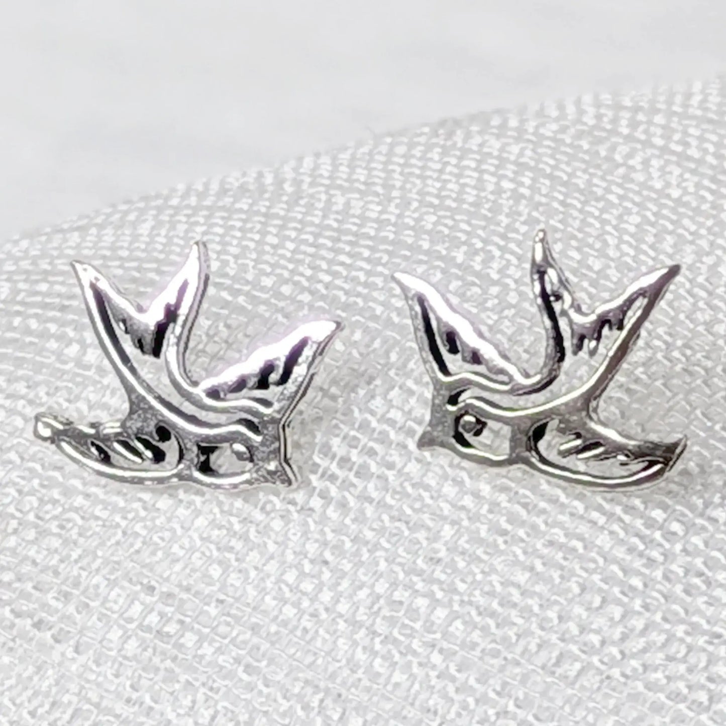 Nahaufnahme von filigranen Schwalben-Ohrsteckern aus 925 Sterling Silber mit Cut-Out-Details.