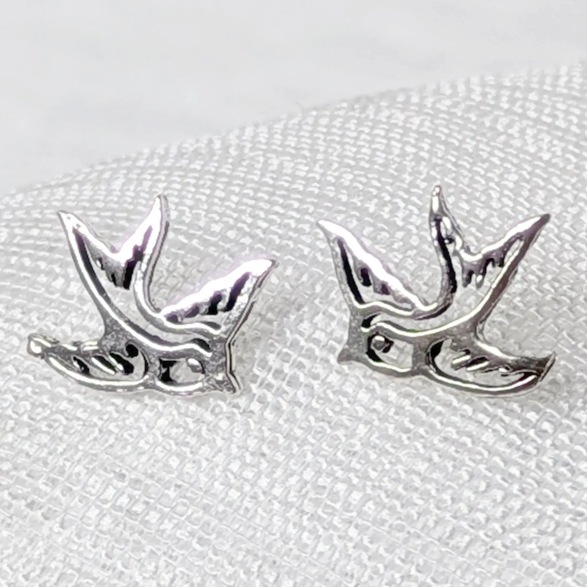 Nahaufnahme von filigranen Schwalben-Ohrsteckern aus 925 Sterling Silber mit Cut-Out-Details.