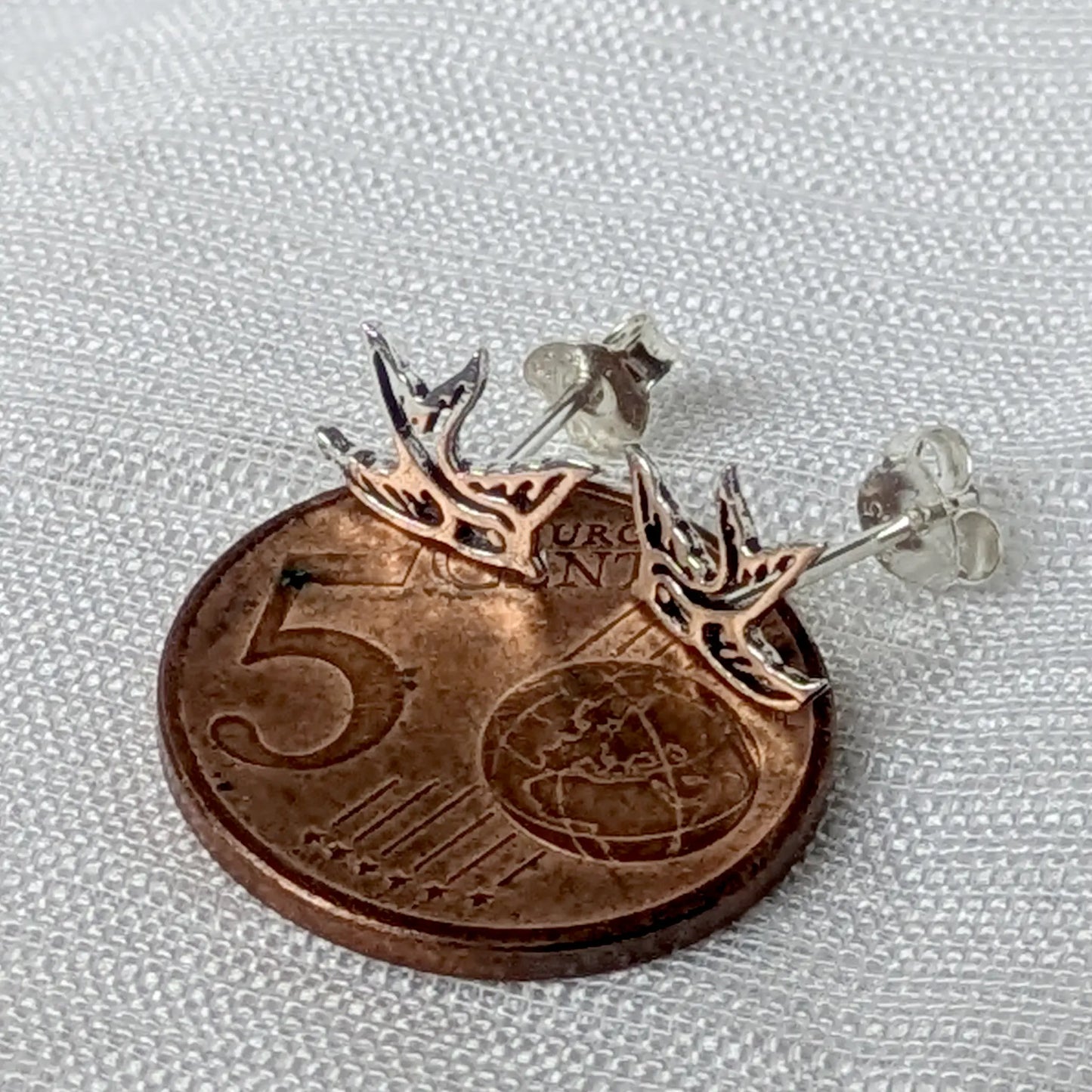 Größenvergleich der zierlichen Schwalben-Ohrstecker aus Silber auf einer 5-Cent-Münze.
