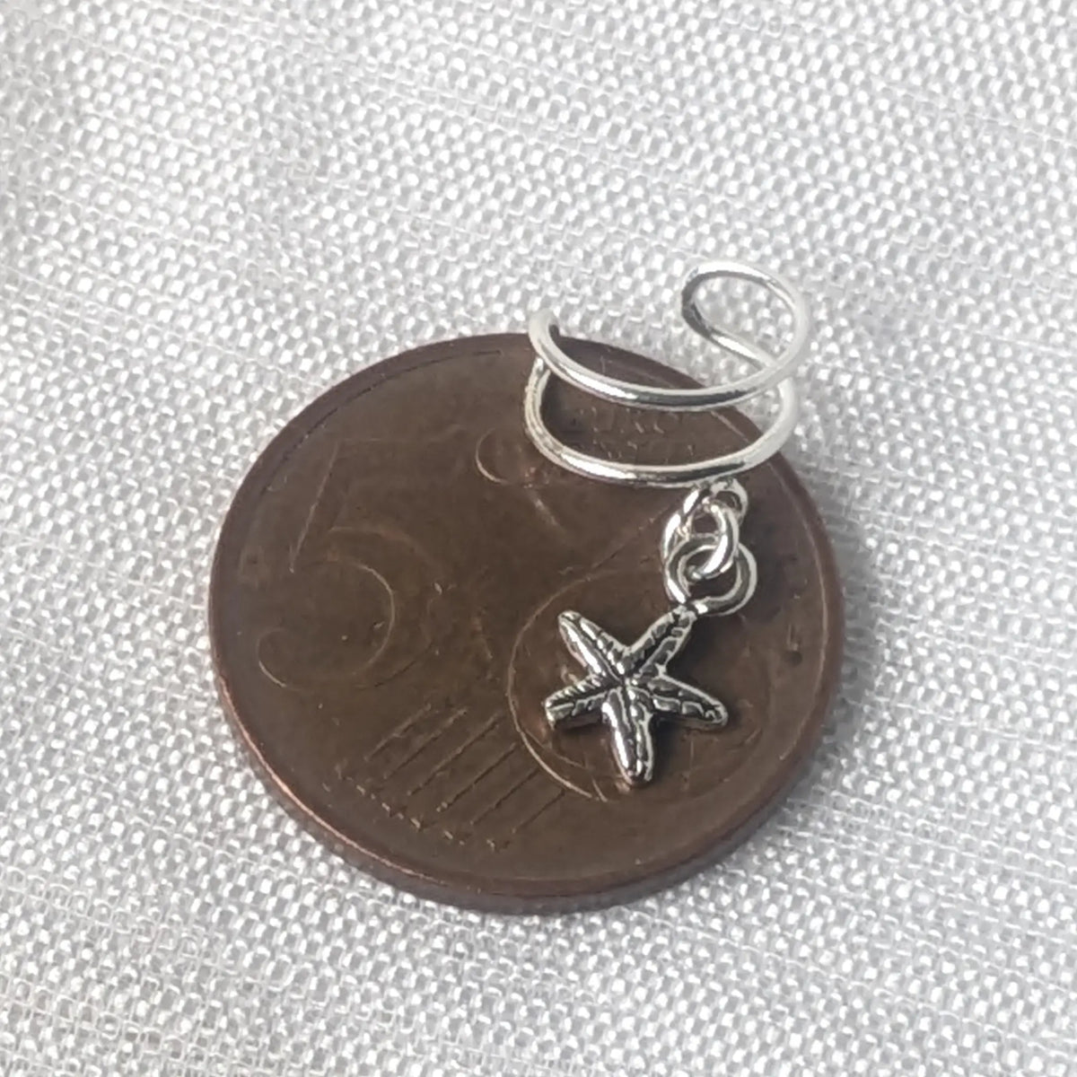 Größenvergleich eines maritimen Silber Ear Cuffs mit Seestern flach auf einer 5-Cent-Münze liegend.