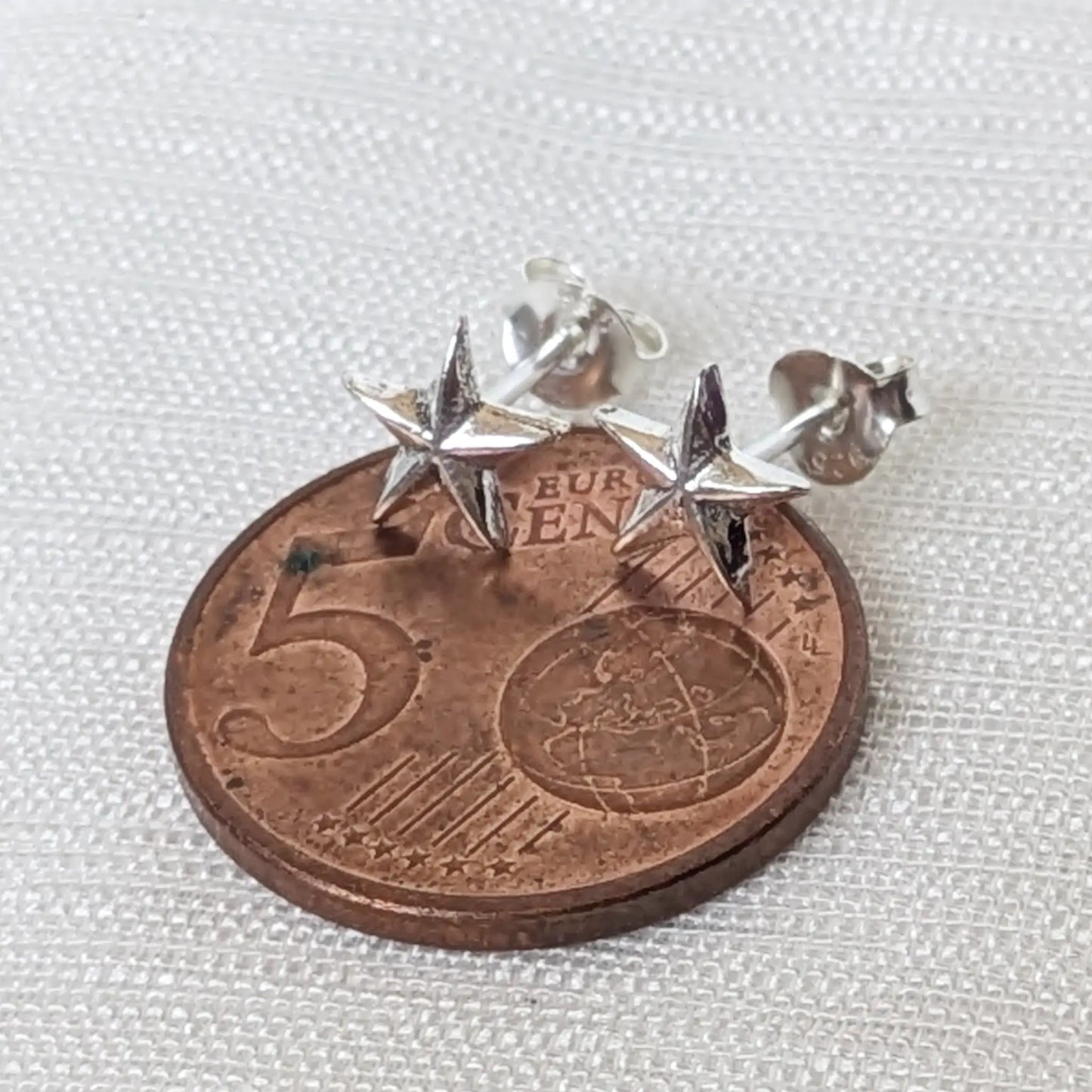Direkter Größenvergleich der filigranen Seestern-Silberohrringe auf einer 5-Cent-Münze.