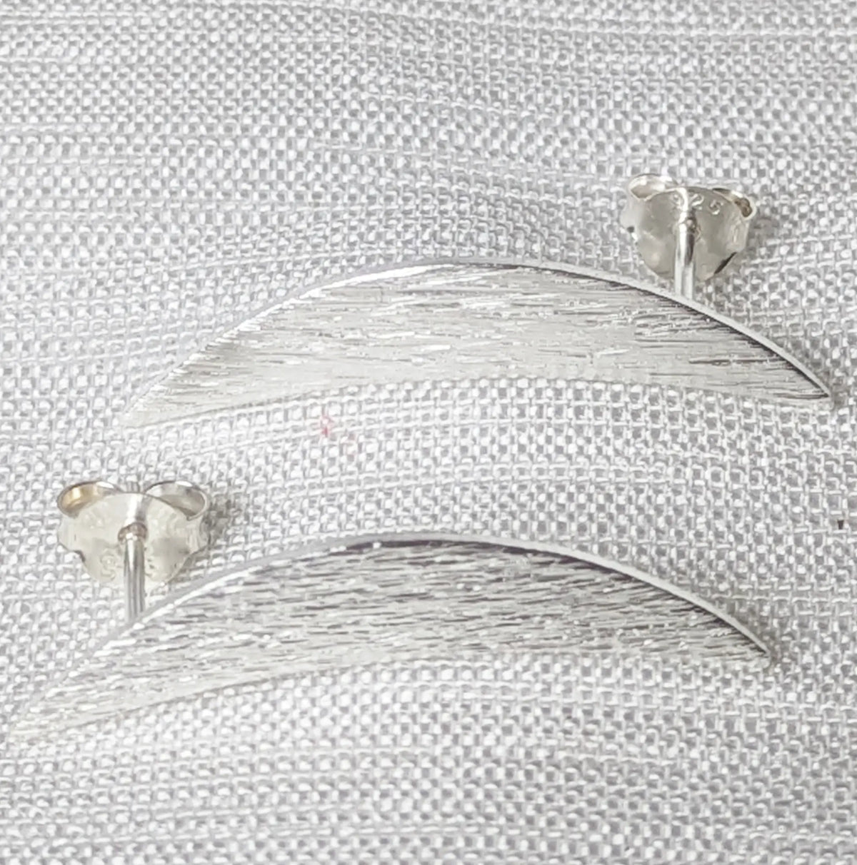 Frontalansicht längliche Silber Ohrstecker in moderner Sichelform für Damen