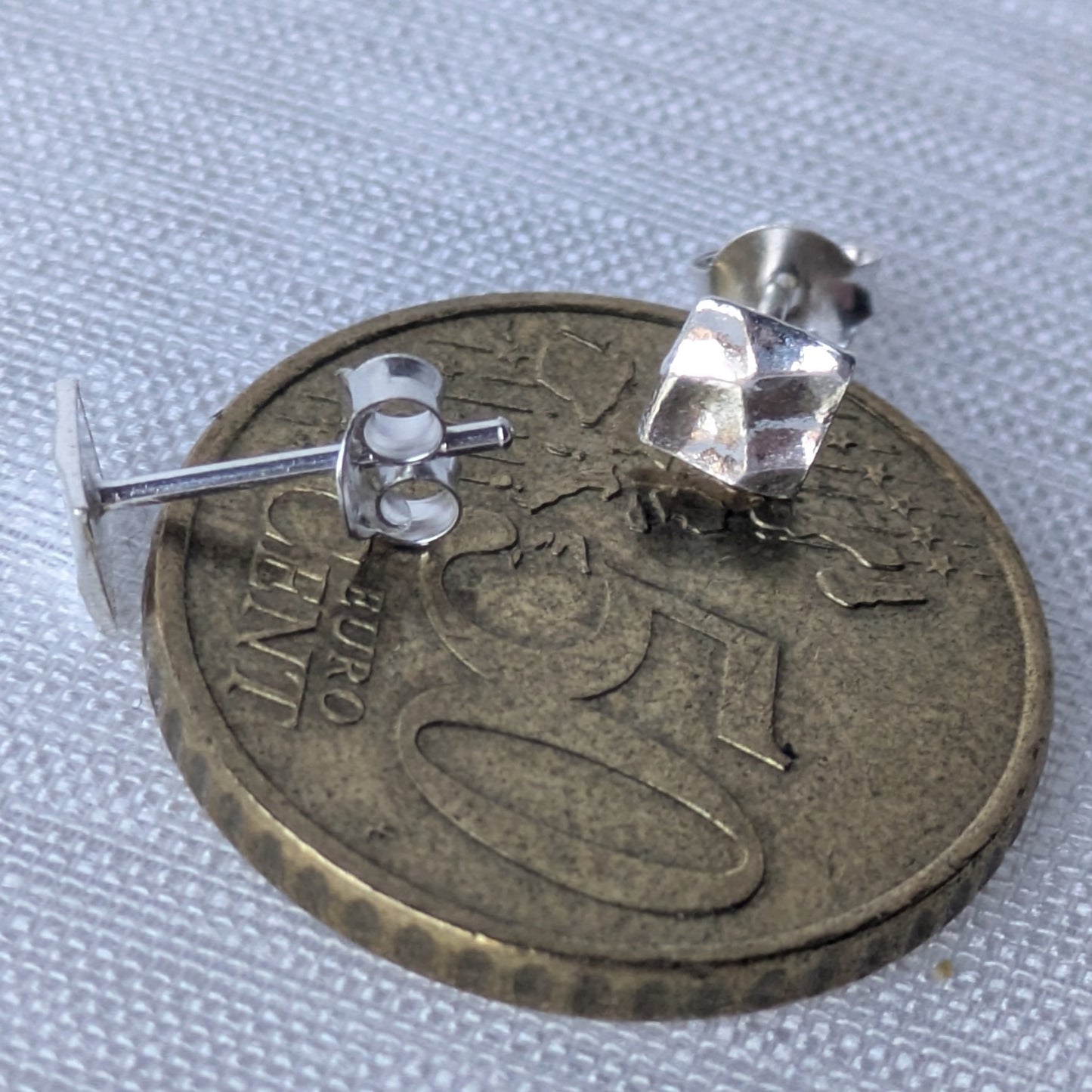 Zwei quadratische Ohrstecker aus 925-Silber, präsentiert auf 50-Cent Münze