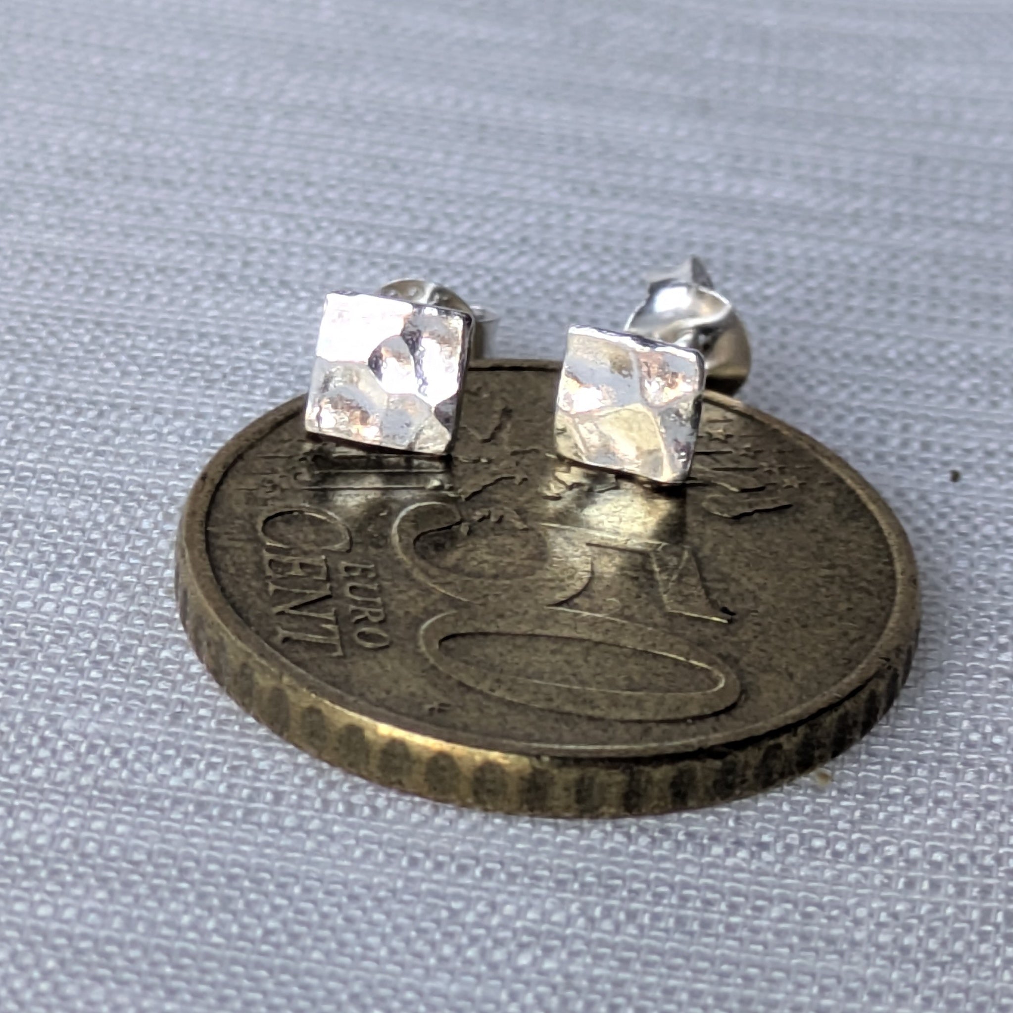 Aufnahme der strukturierten Silber-Ohrstecker, die das Licht unregelmäßig reflektieren