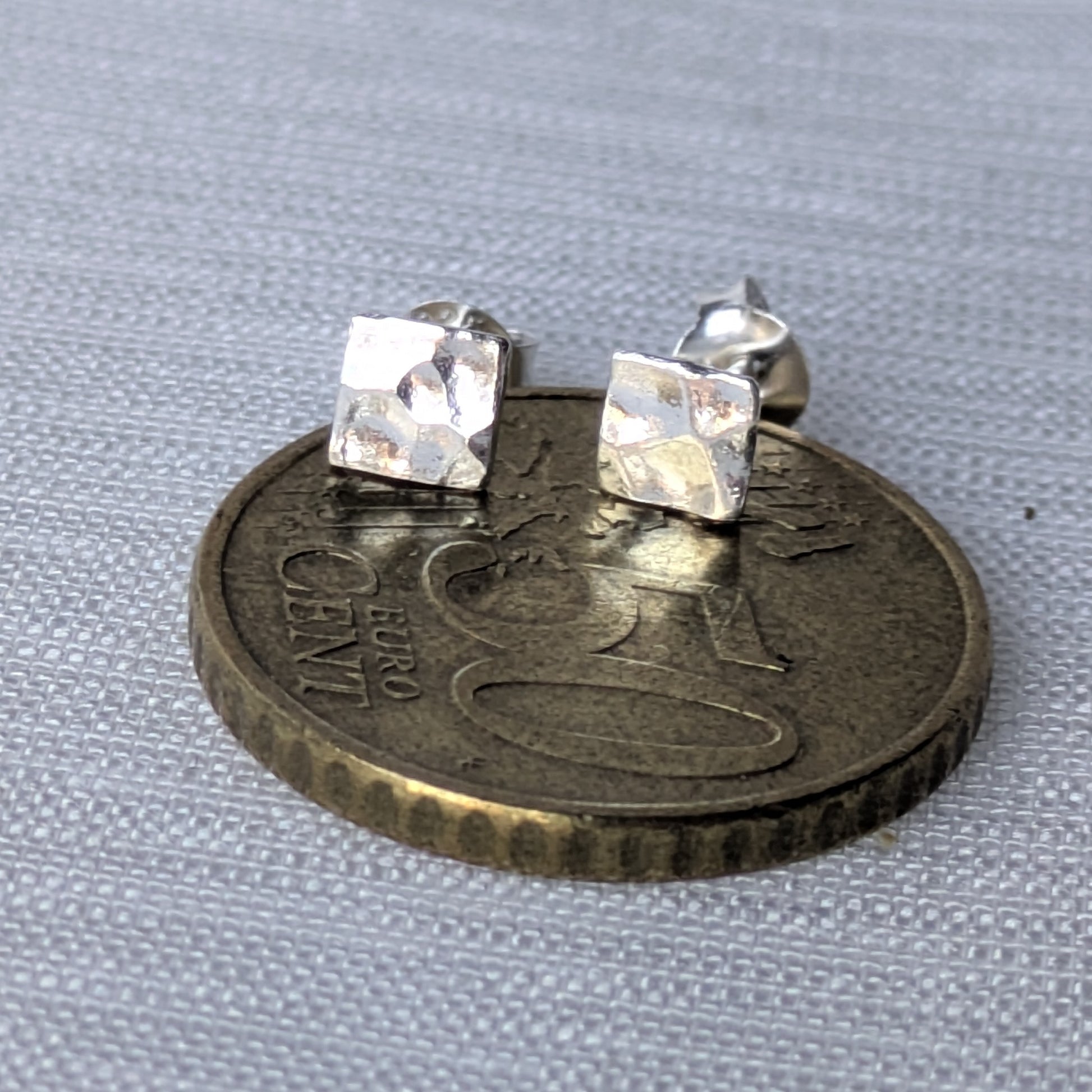 Aufnahme der strukturierten Silber-Ohrstecker, die das Licht unregelmäßig reflektieren