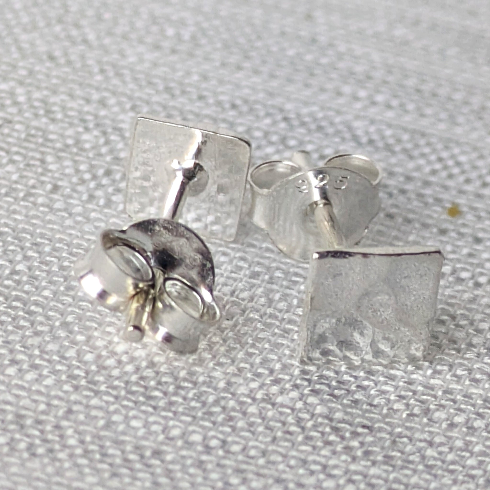 Detailansicht der strukturierten Silber-Ohrstecker mit reflektierender, handwerklicher Oberfläche.