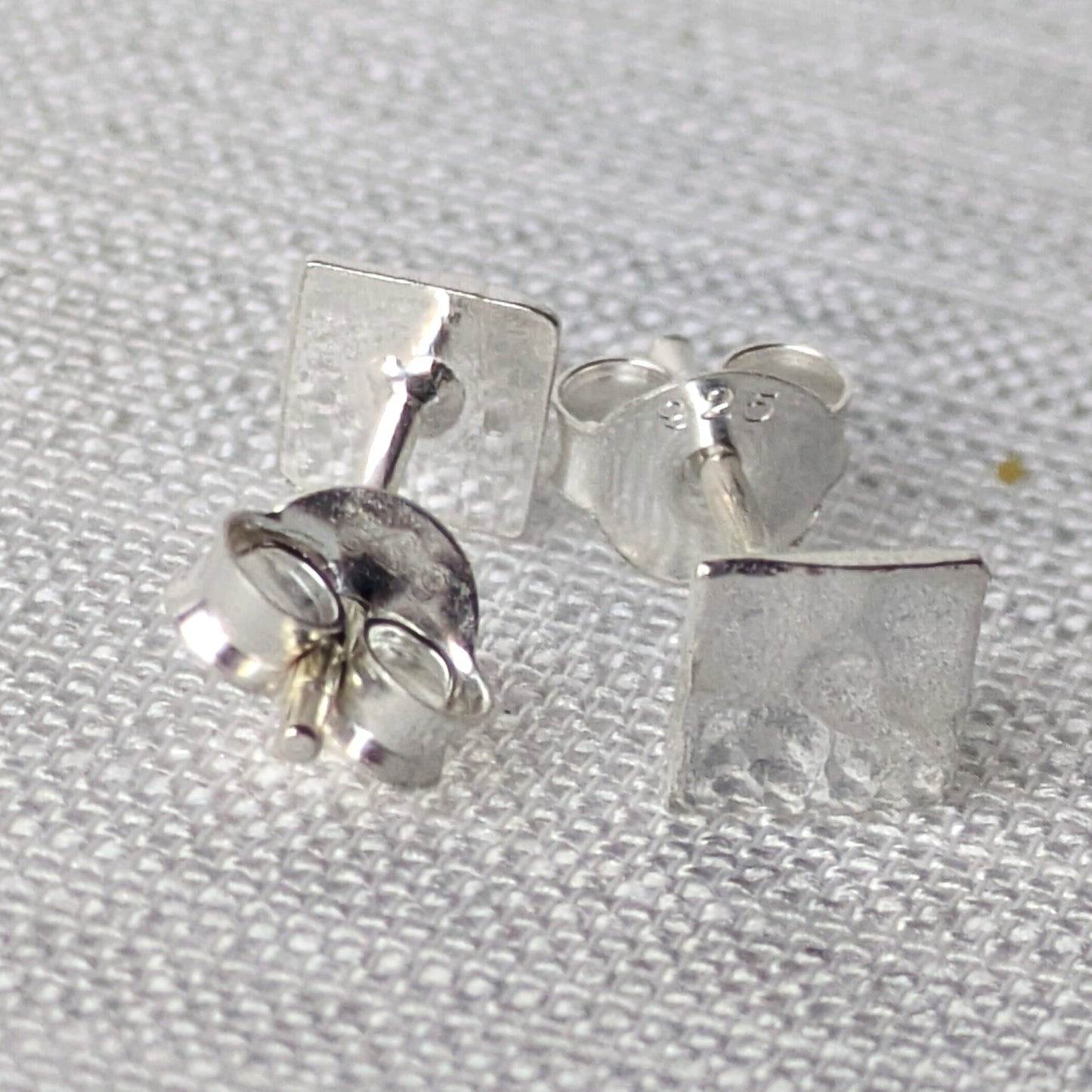 Detailansicht der strukturierten Silber-Ohrstecker mit reflektierender, handwerklicher Oberfläche.