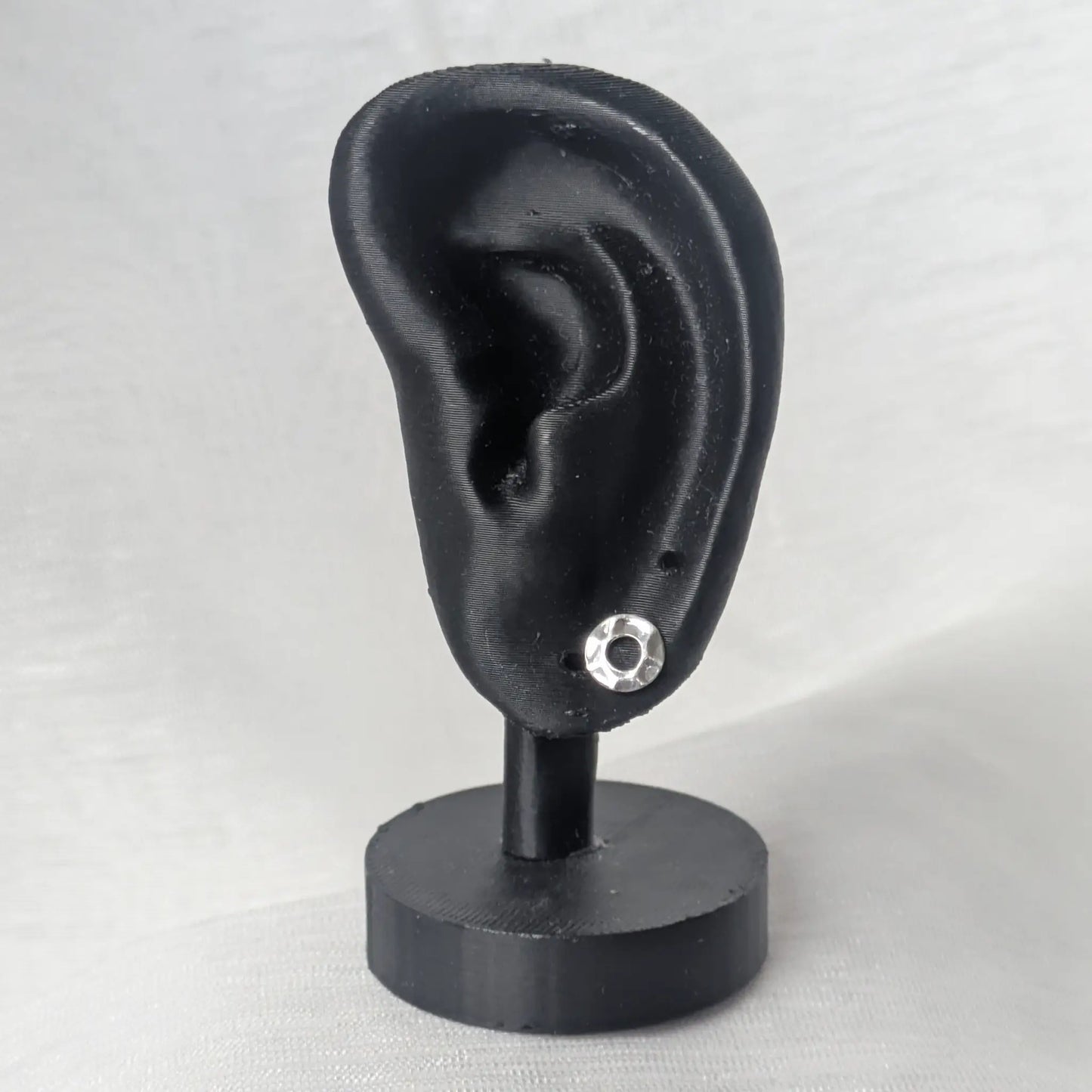 Silberne Karma-Ohrstecker präsentiert an einem schwarz