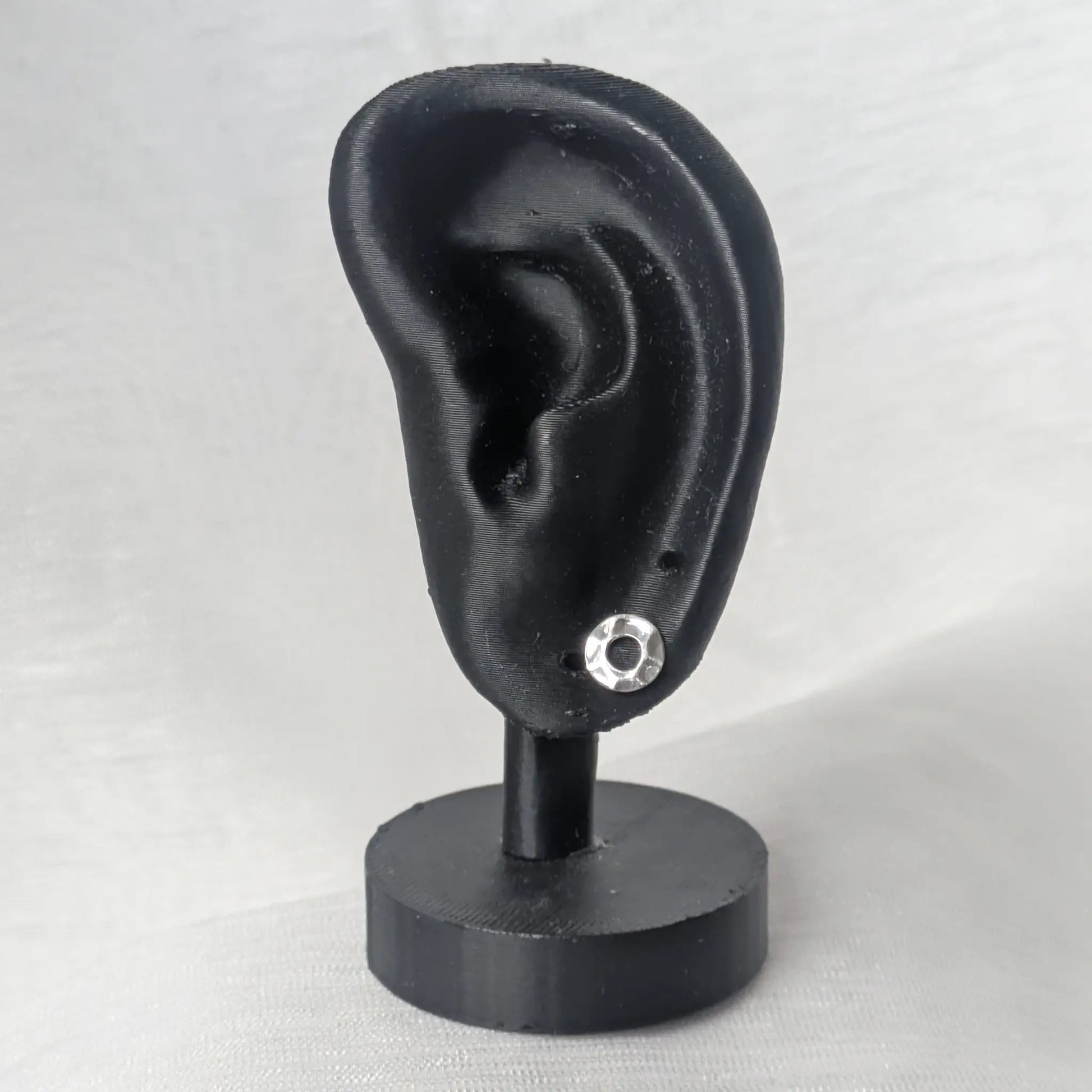 Silberne Karma-Ohrstecker präsentiert an einem schwarz