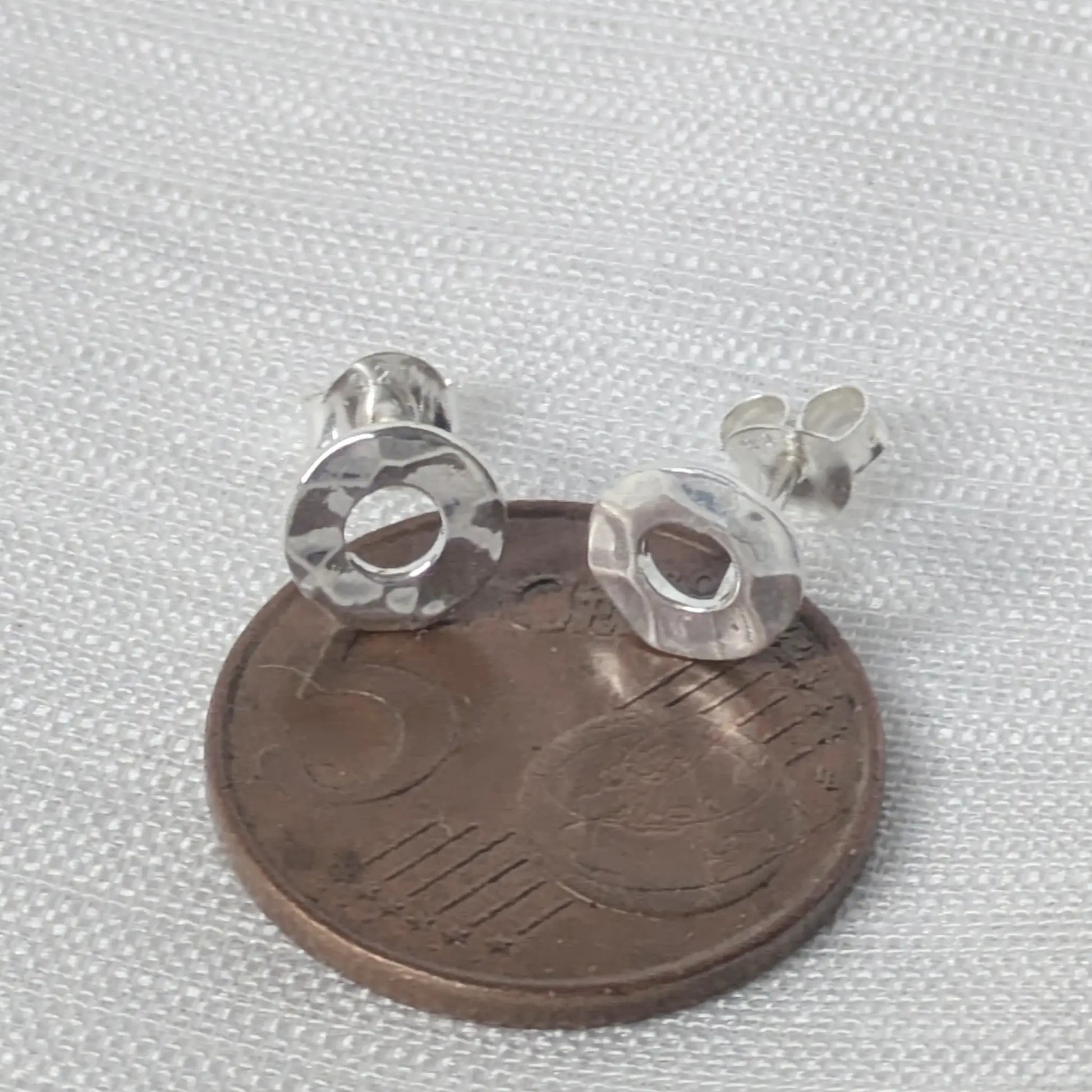 Größenvergleich der kreisförmigen Silber-Ohrstecker auf einer Cent-Münze.
