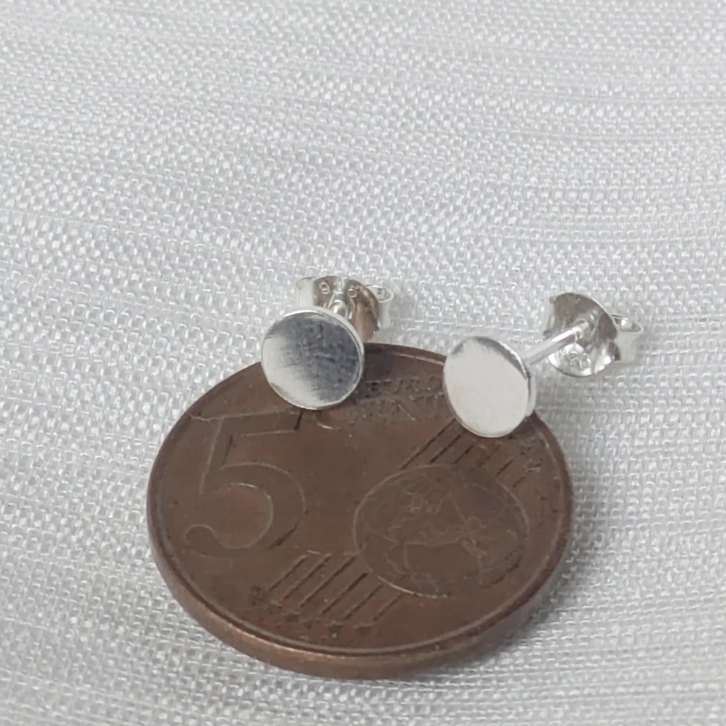 Größenvergleich der kleinen flachen Silber-Plättchen auf einer Cent-Münze.