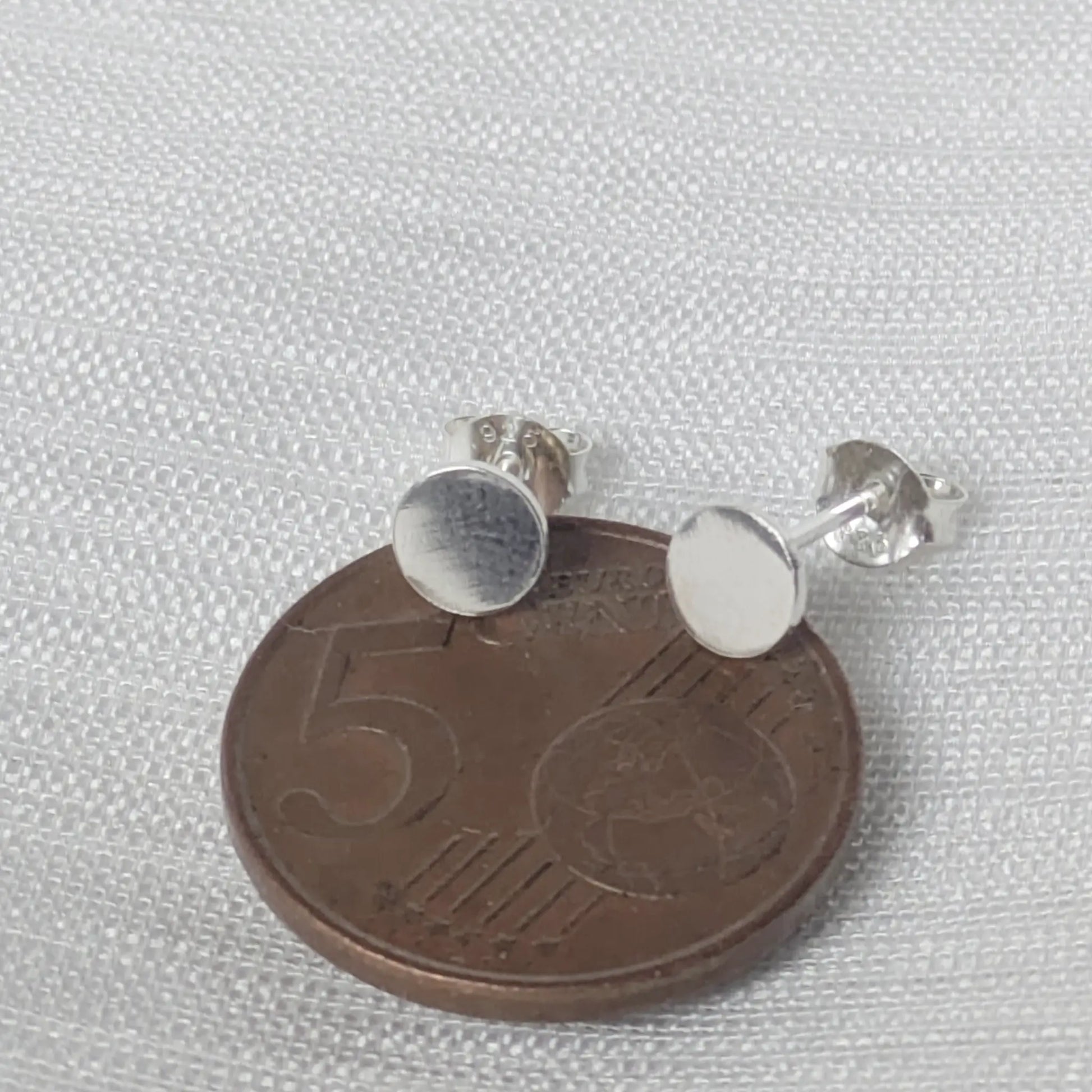 Größenvergleich der kleinen flachen Silber-Plättchen auf einer Cent-Münze.
