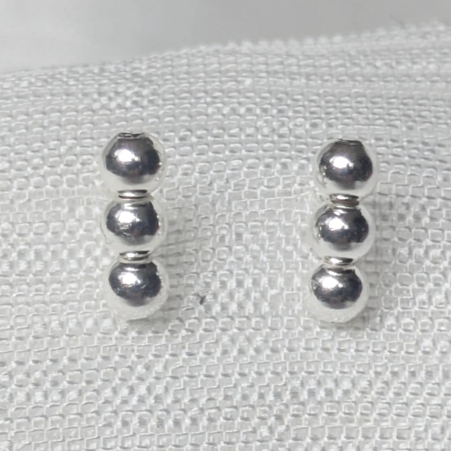 Nahaufnahme 925 Silber Ohrstecker mit drei glänzenden Kugeln.