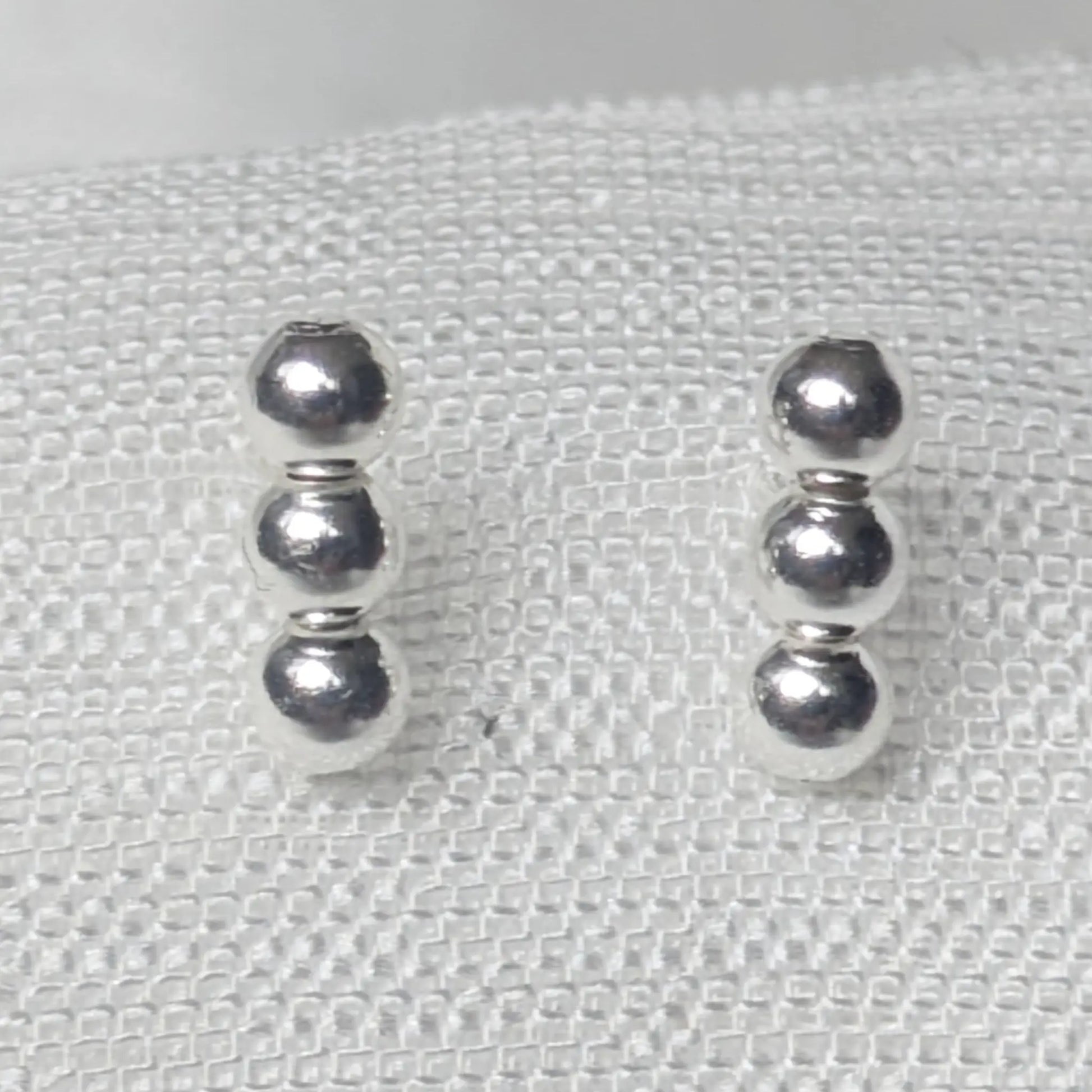 Nahaufnahme 925 Silber Ohrstecker mit drei glänzenden Kugeln.