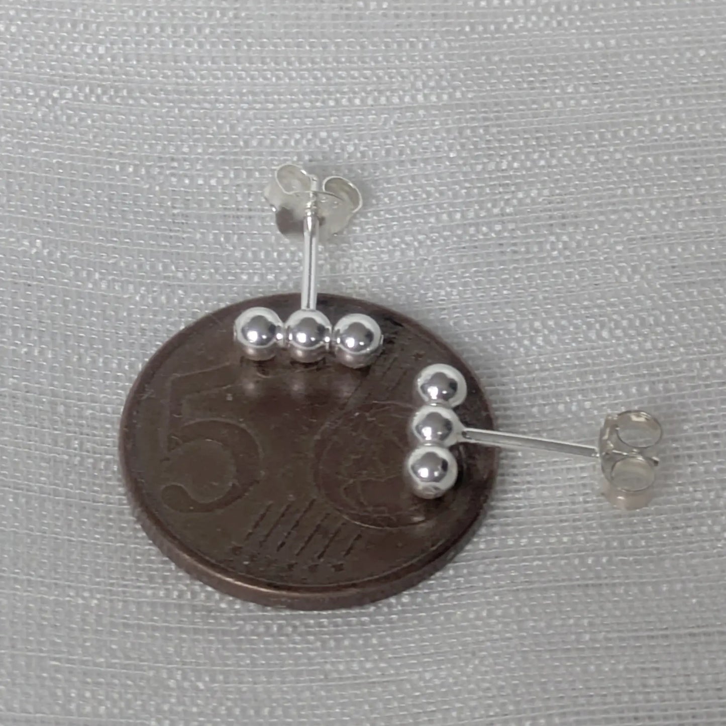 Größenvergleich der kleinen Silber Ohrstecker auf einer 5-Cent-Münze.