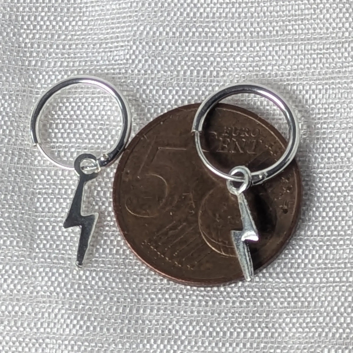 Größenvergleich der zierlichen Silbercreolen mit Blitz-Anhänger, flach liegend auf einer 5-Cent-Münze.