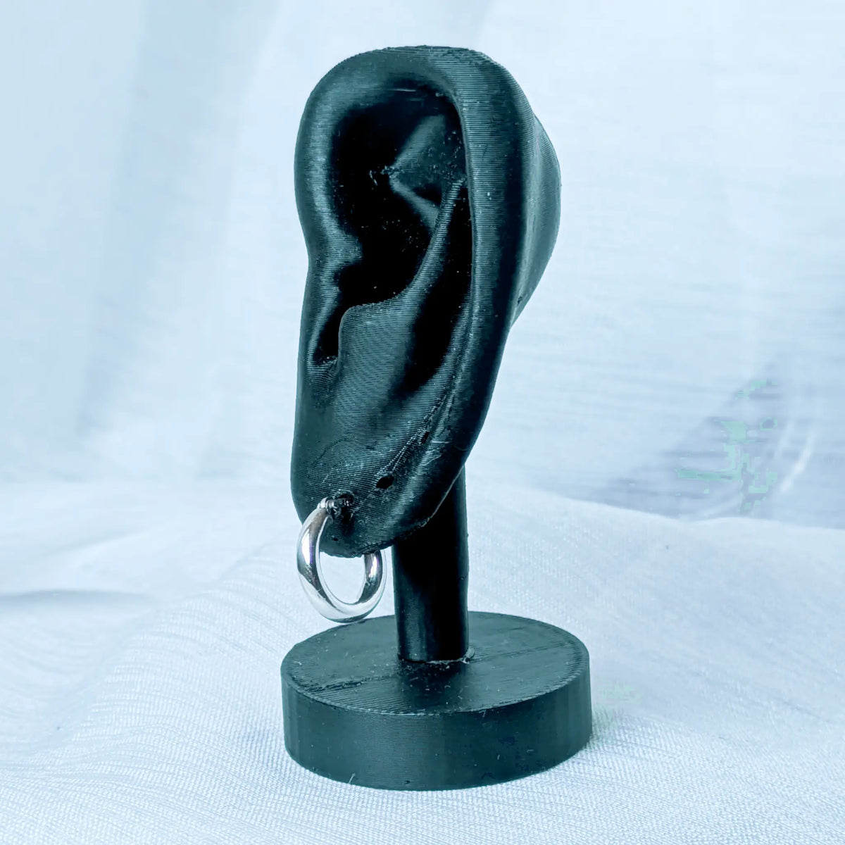 Eine markante, 3mm dicke Silbercreole, Durchmesser 10mm, elegant und auffällig an einem schwarzen 3D-Ohr-Display präsentiert.