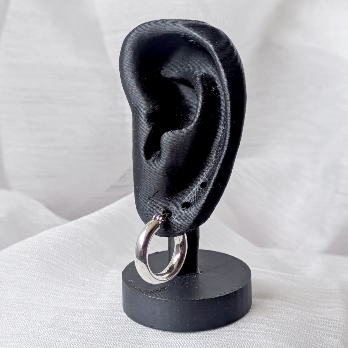 Eine markante, 3mm dicke Silbercreole, Durchmesser 20mm, elegant und auffällig an einem schwarzen 3D-Ohr-Display präsentiert.