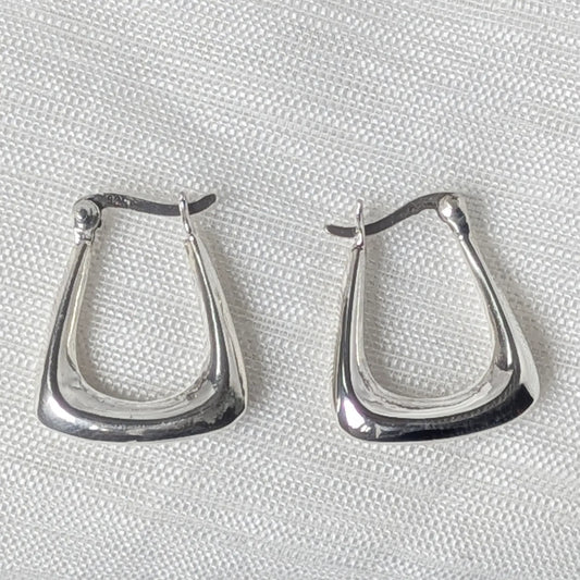 Nahaufnahme von zwei eckigen Klappcreolen aus poliertem 925 Silber im geometrischen Design.