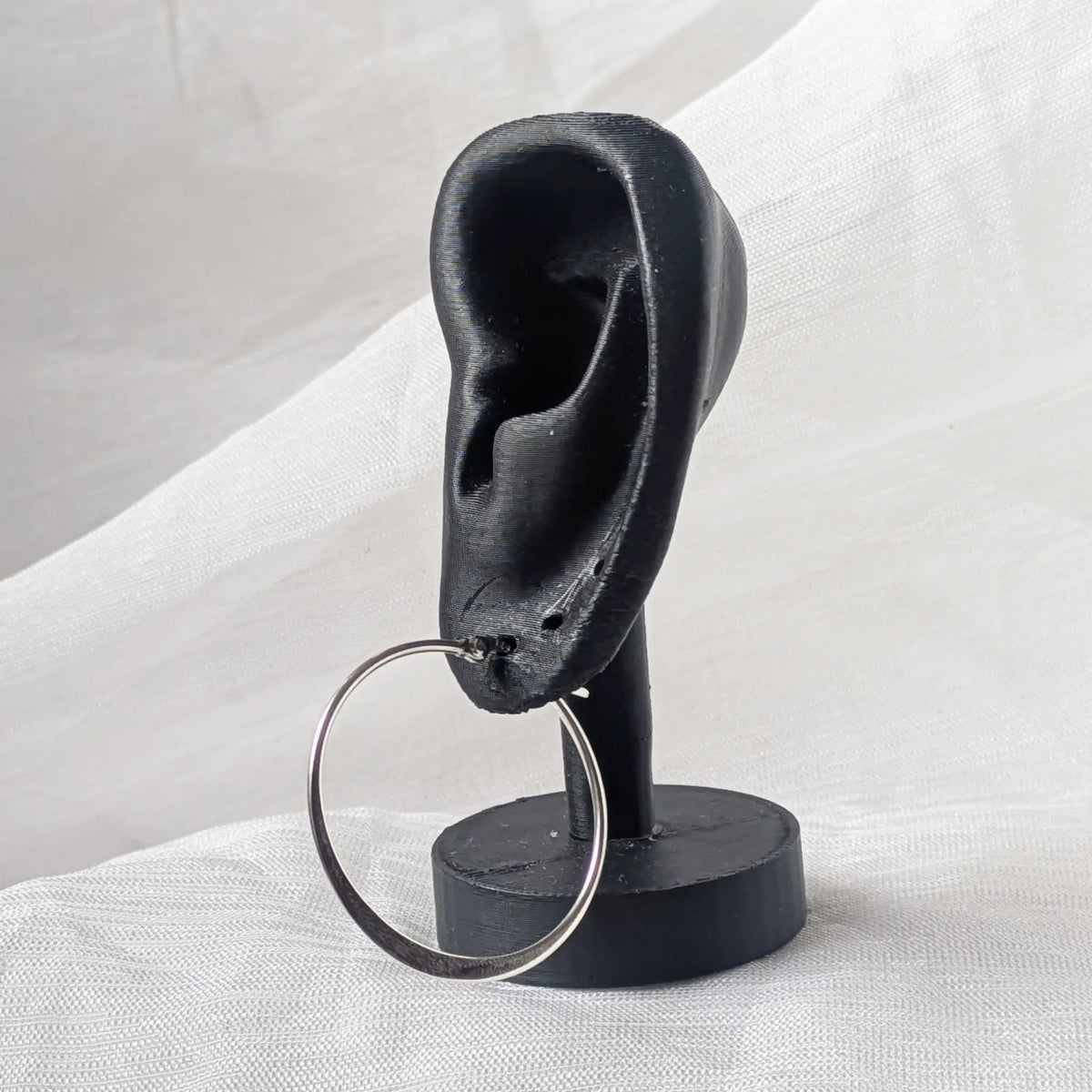 Eine moderne, unten flache 35mm Silbercreole stilvoll präsentiert an einem schwarzen 3D-Ohr-Display.