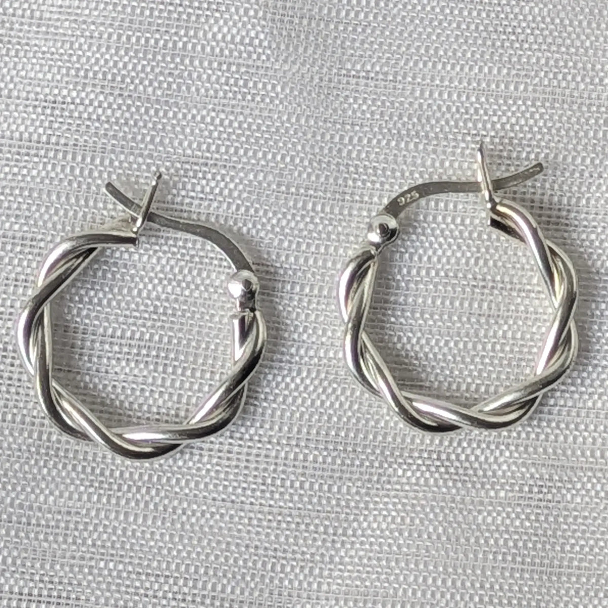 Nahaufnahme von zwei glänzenden 925 Silber Creolen im gedrehten Kordel-Design.
