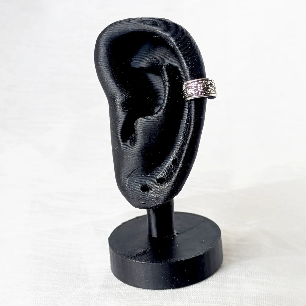Silberner Ear Cuff im Sonne-Stern-Design, getragen an der Helix eines schwarzen 3D-gedruckten Ohr-Displays