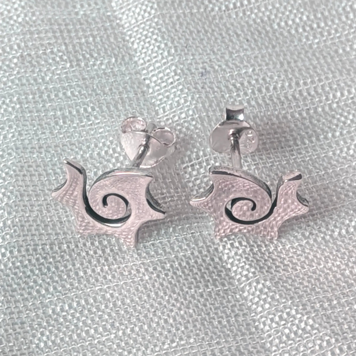 Frontalansicht der glänzenden Sonnenwirbel-Ohrstecker aus 925 Sterlingsilber mit feinen Zacken und geschwungener Mitte.