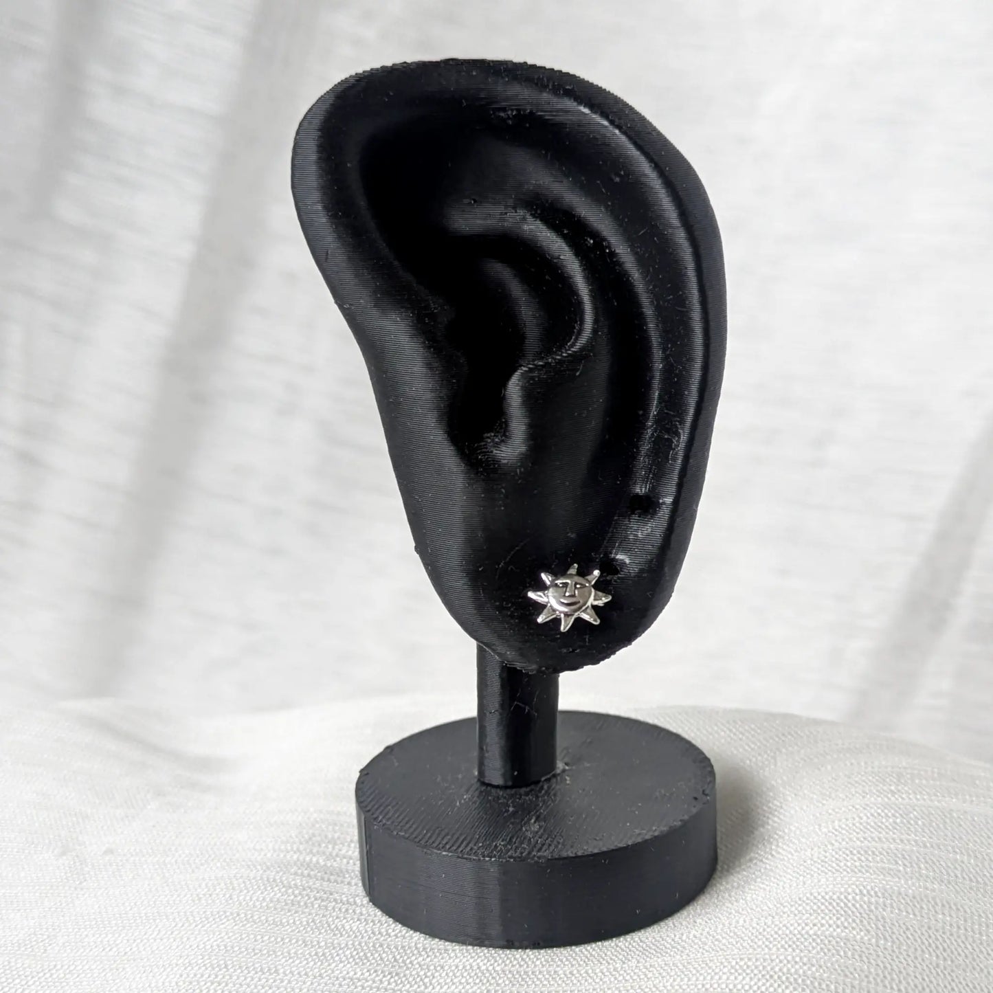 Ein 925 Silber Sonnen-Ohrstecker an einem schwarzen, anatomisch geformten Ohr-Display zur Größenvisualisierung