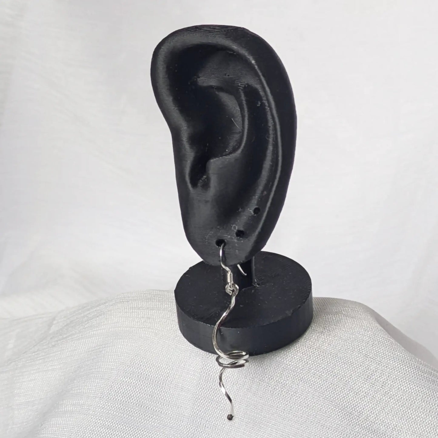 Lange silberne Spiral-Ohrhänger elegant präsentiert am schwarzen Ohr-Display.