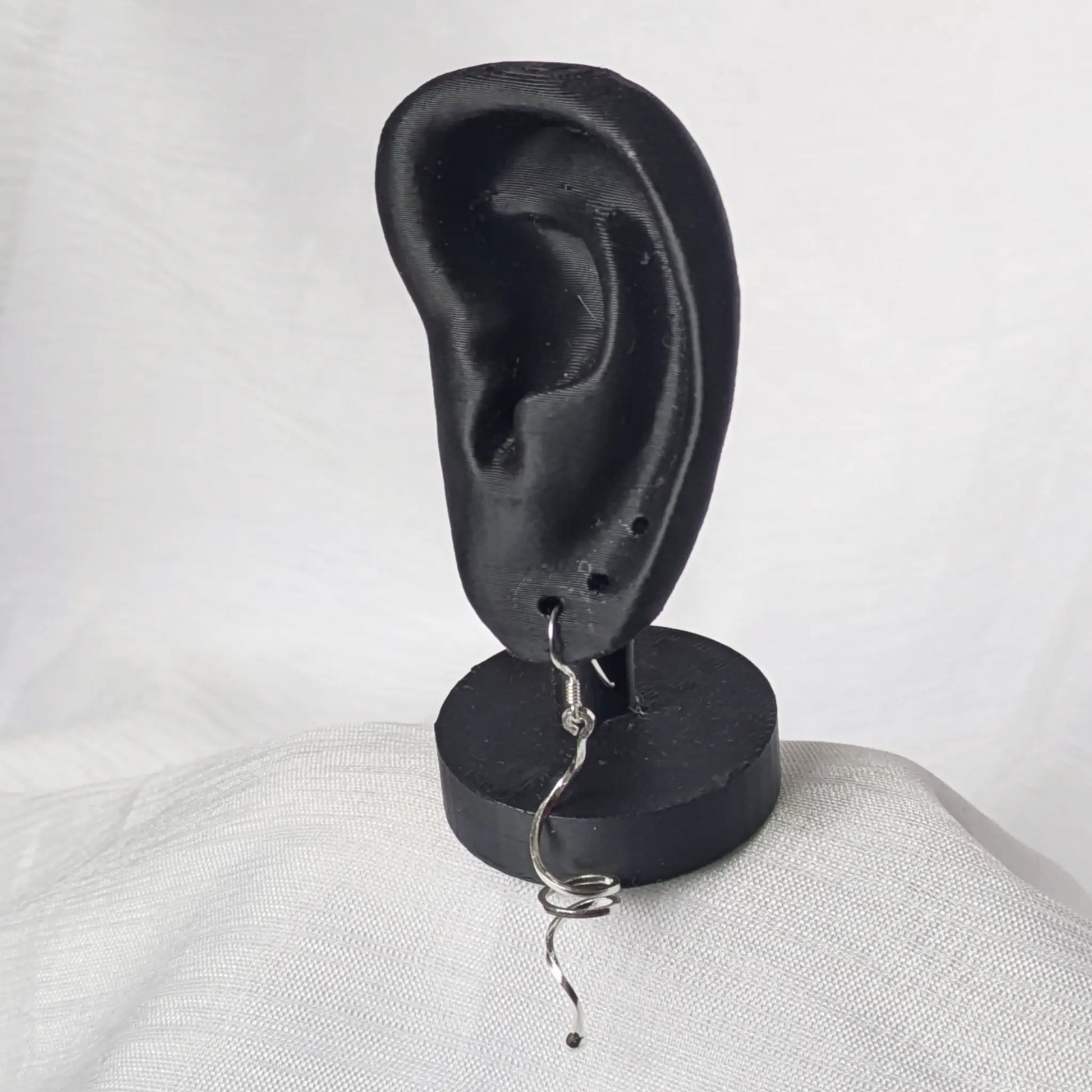 Lange silberne Spiral-Ohrhänger elegant präsentiert am schwarzen Ohr-Display.
