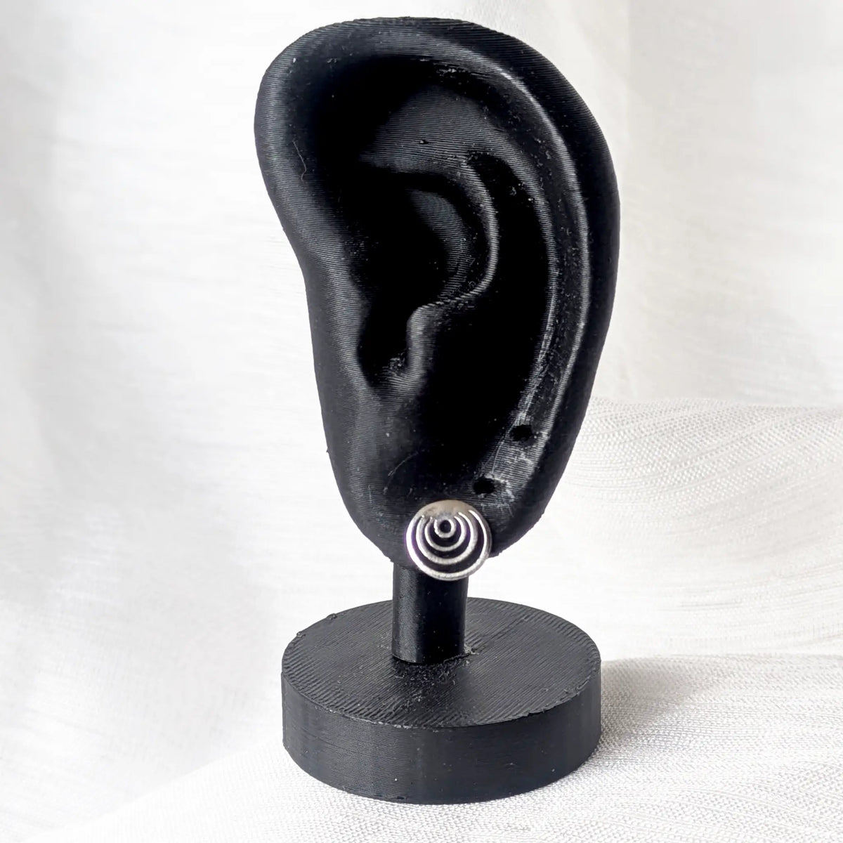 Geometrische Silber-Ohrstecker am schwarzen 3D-Ohr-Display zur Veranschaulichung der dezenten Größe und Passform.