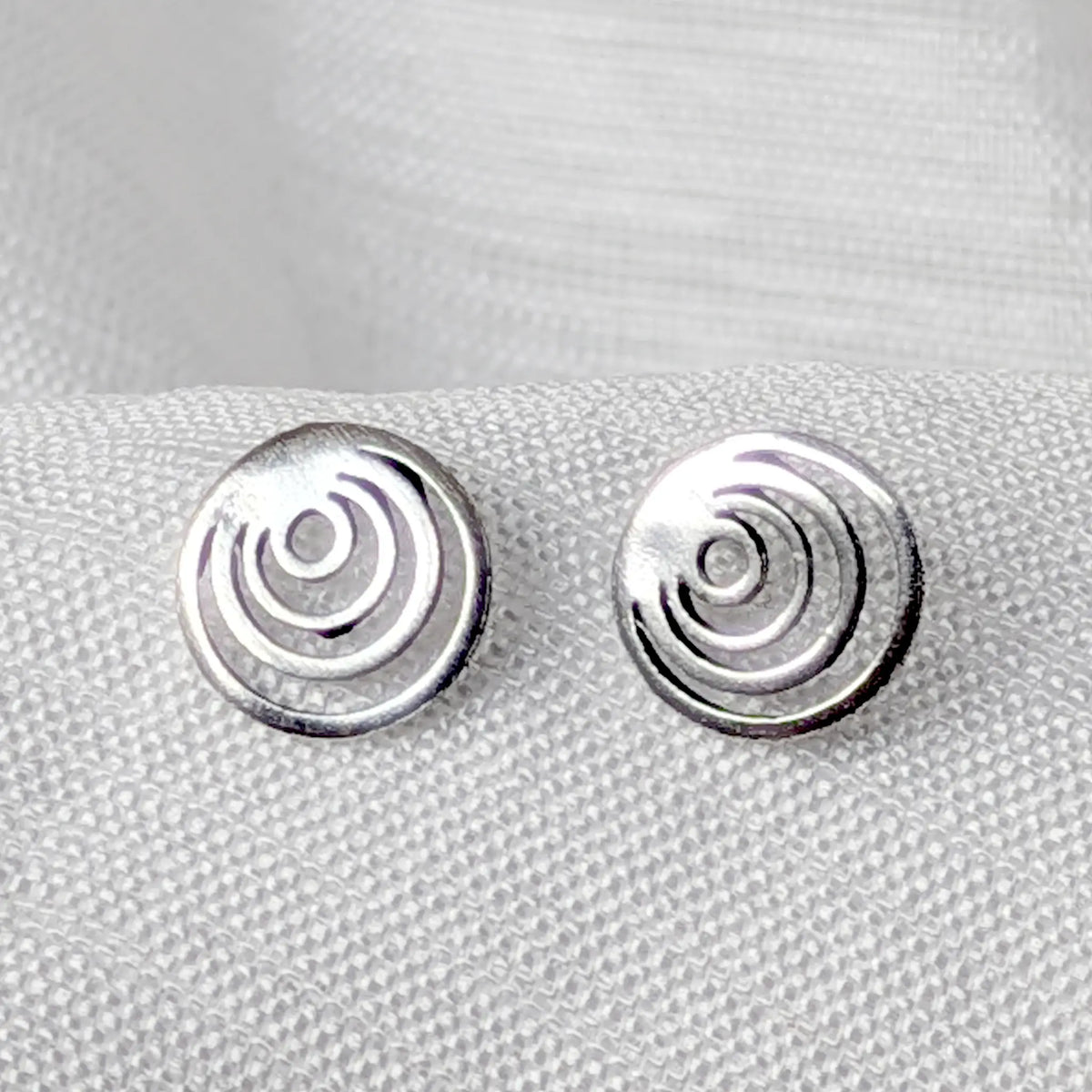 Nahaufnahme runder 925 Silber Ohrstecker mit geometrischem, offenem Kreis-Design auf hellem Stoff.