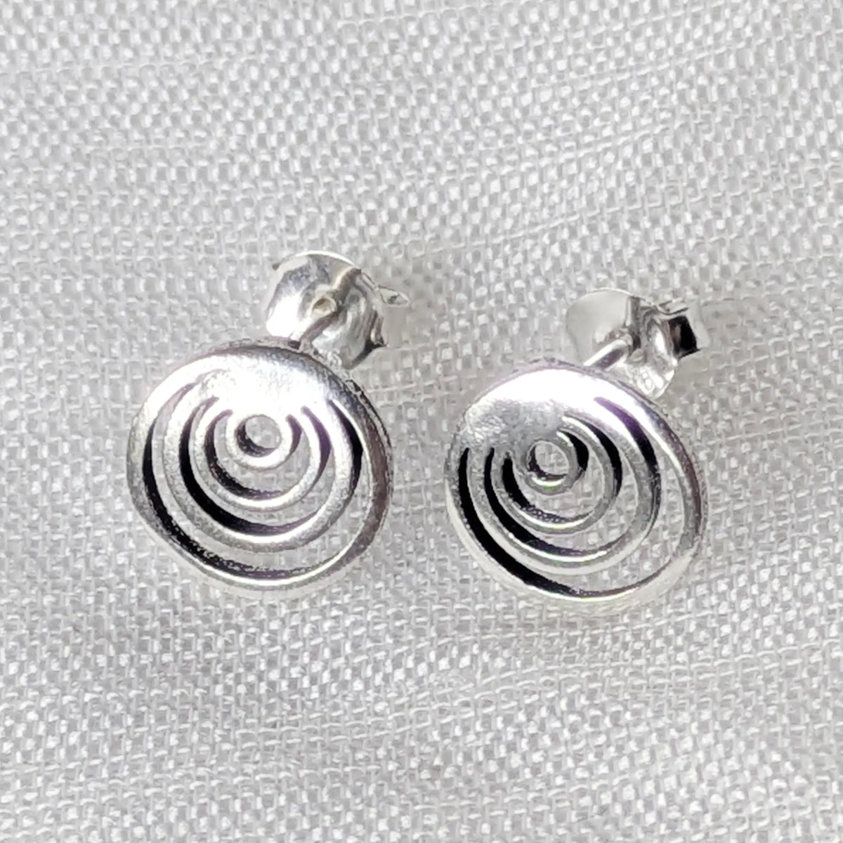 Frontalansicht der konzentrischen Silber-Ohrstecker, die das feine, moderne Spiralmuster deutlich zeigt.