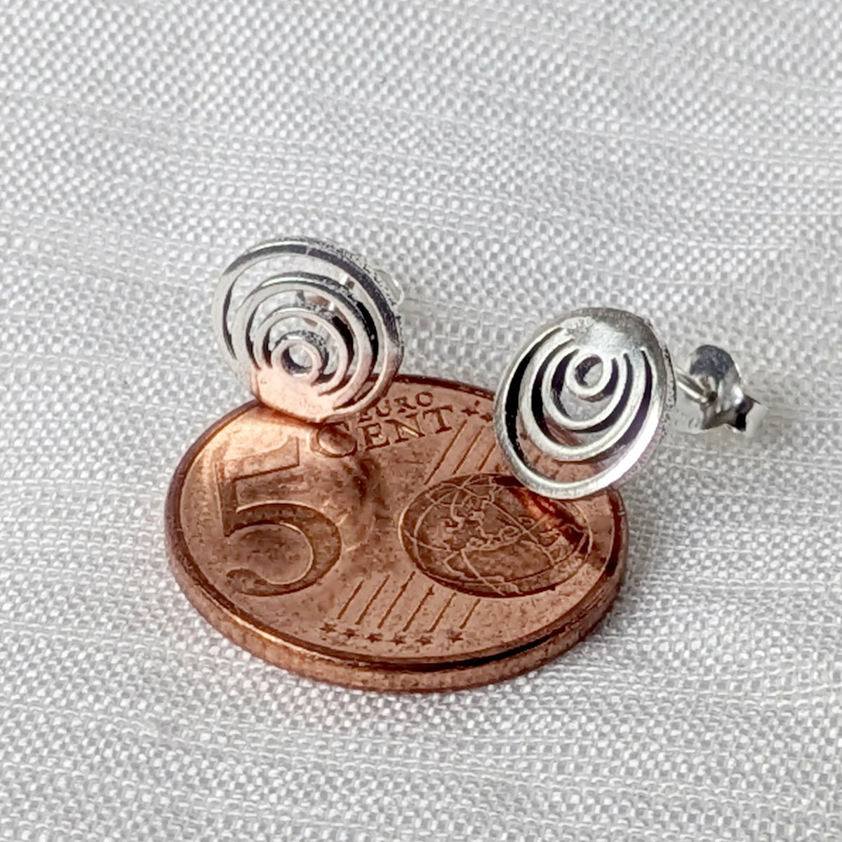 Moderne 925 Silber-Ohrstecker im direkten Größenvergleich flach aufliegend auf einer 5-Cent-Münze.