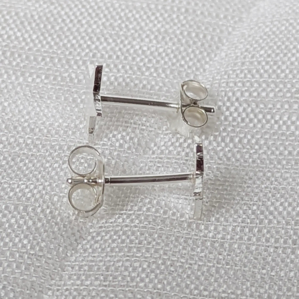 Seitenansicht der flachen Stern Ohrstecker aus Silber, die das eng und sicher anliegende Profil verdeutlicht.
