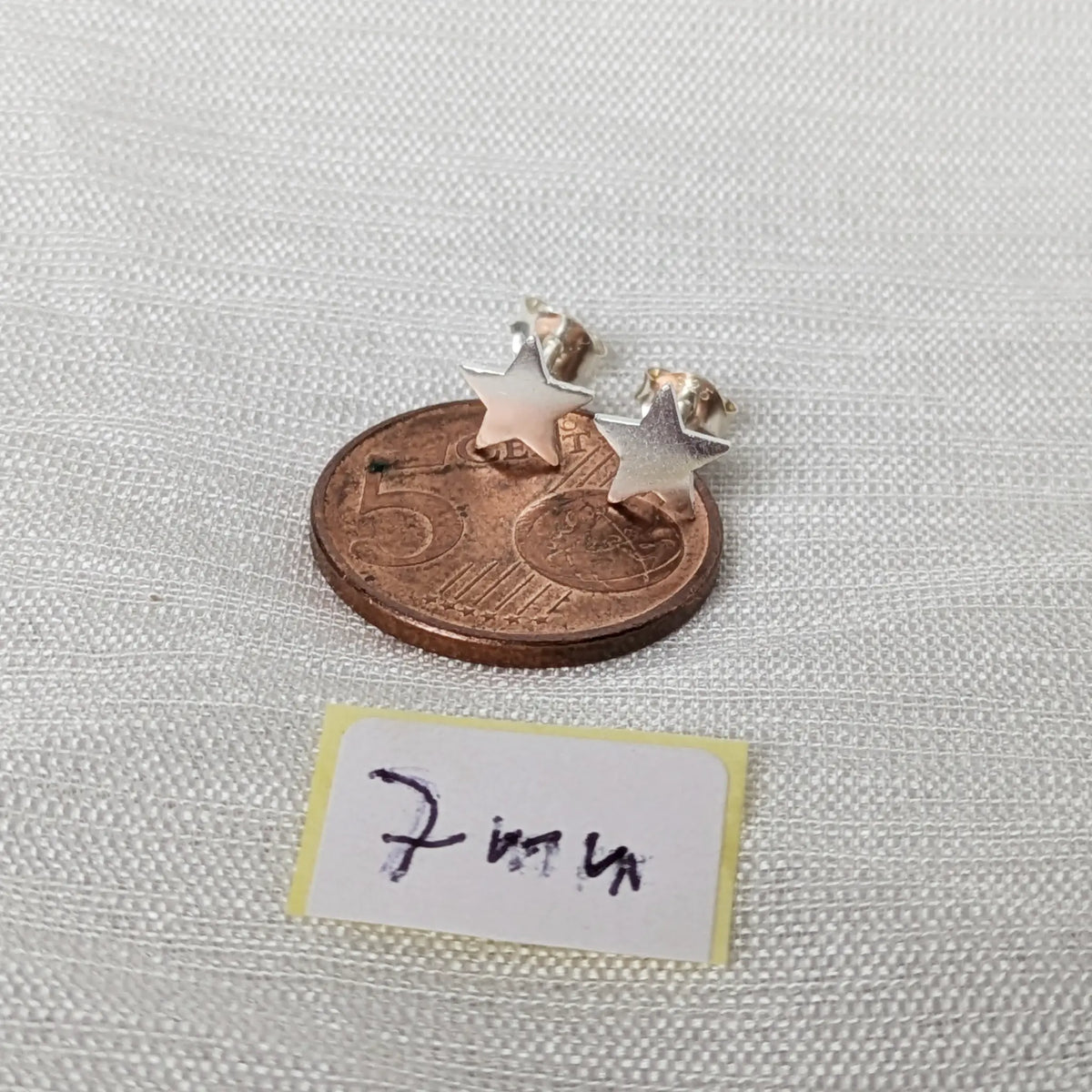 Kleine polierte 7mm Stern Silber-Ohrstecker liegend auf einer 5-Cent-Münze für den exakten Größenvergleich im Alltag.