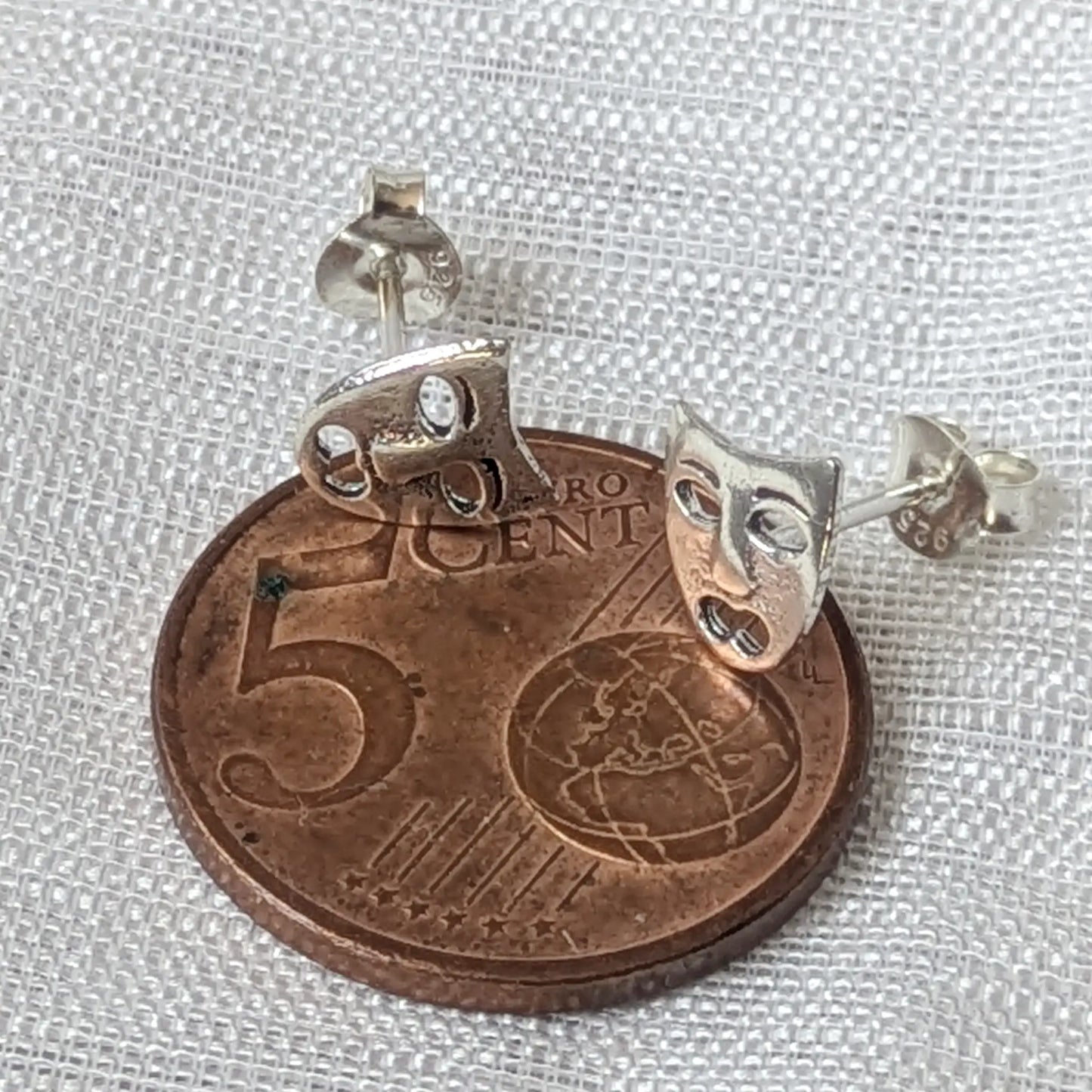Größenvergleich der kleinen, silbernen Tragödie-Ohrstecker platziert auf einer 5-Cent-Münze.