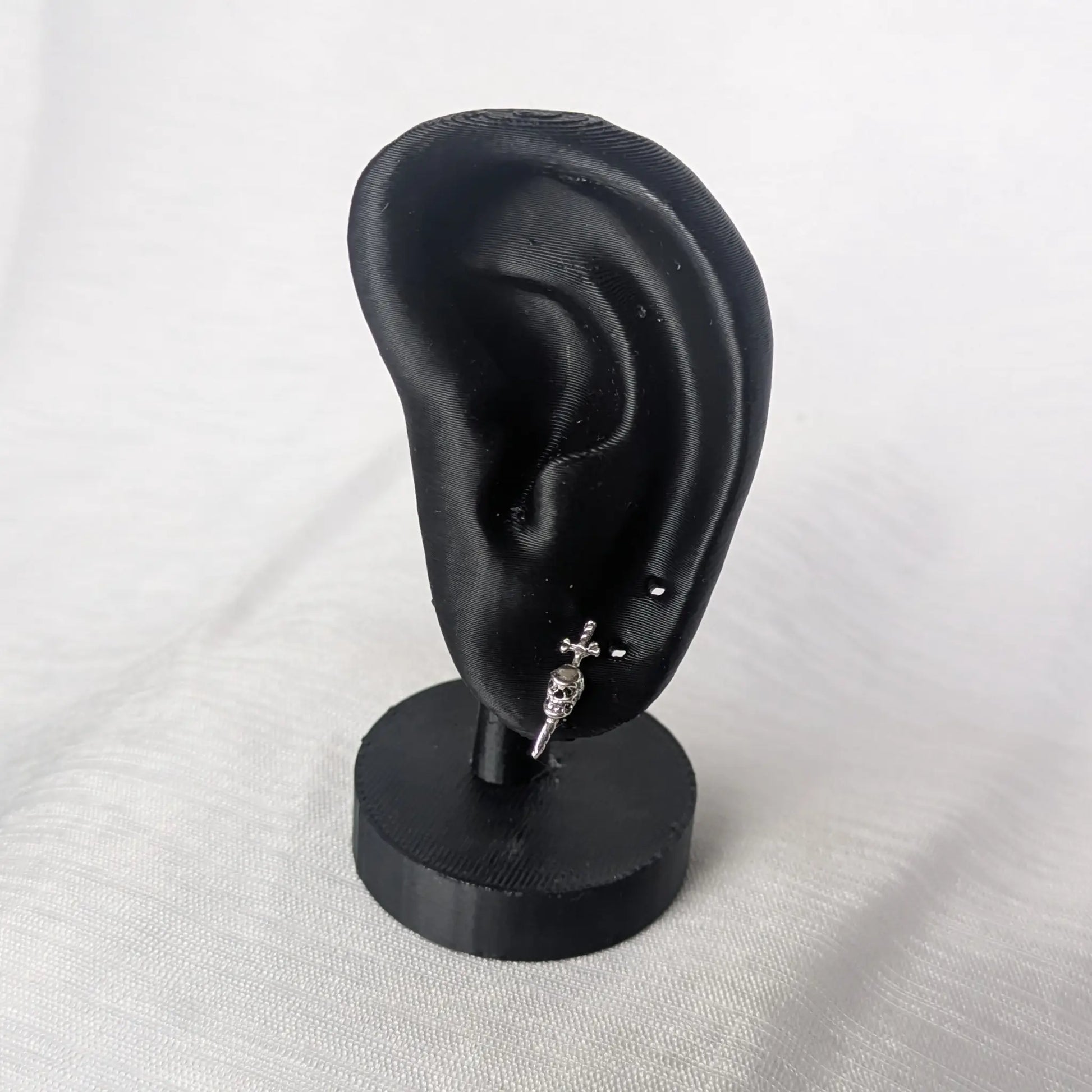 Totenkopf mit Schwert Ohrringe präsentiert an schwarzem Ohr-Display.