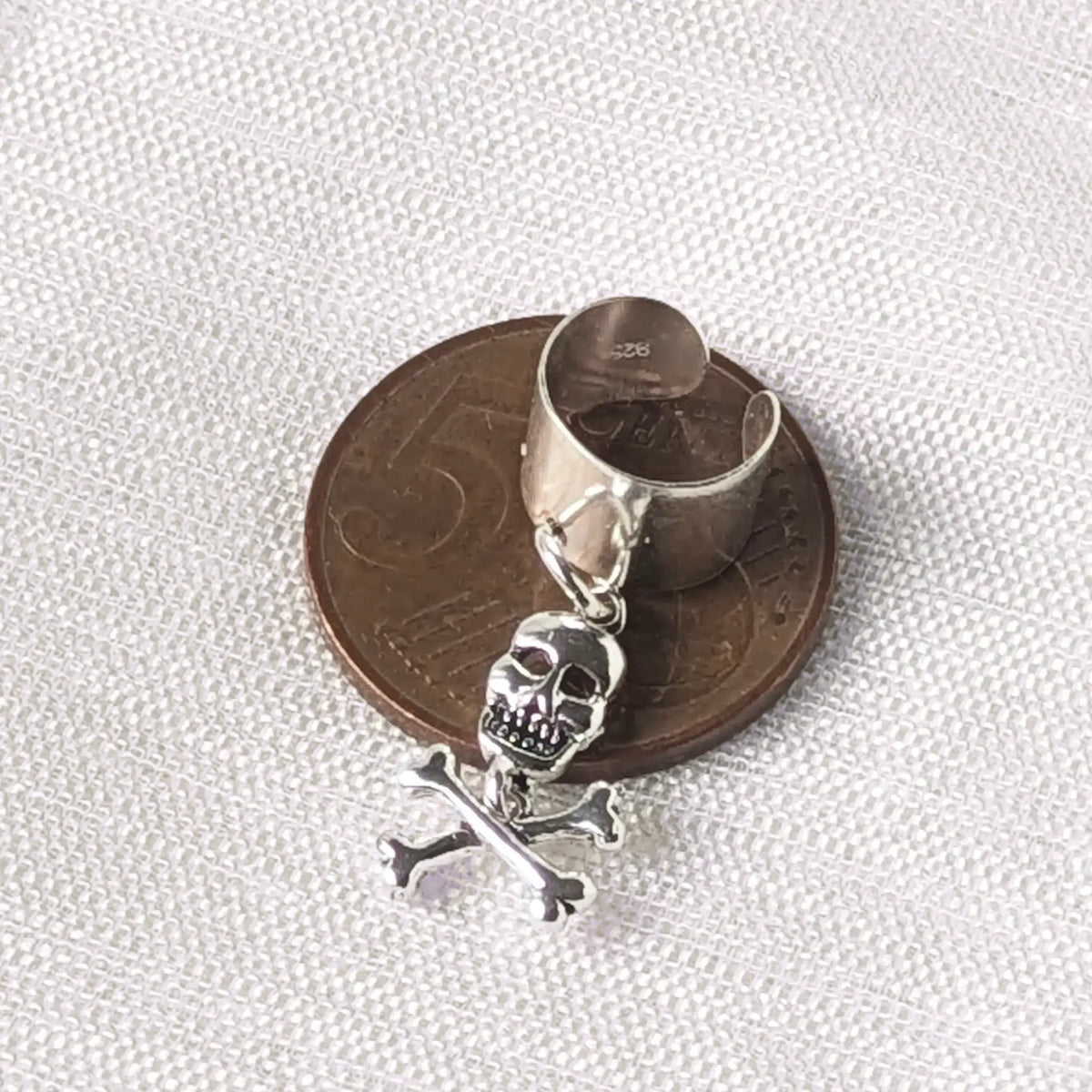Silberner Earcuff mit Totenkopf-Anhänger liegend auf einer 5-Cent-Münze zum präzisen Größenvergleich.
